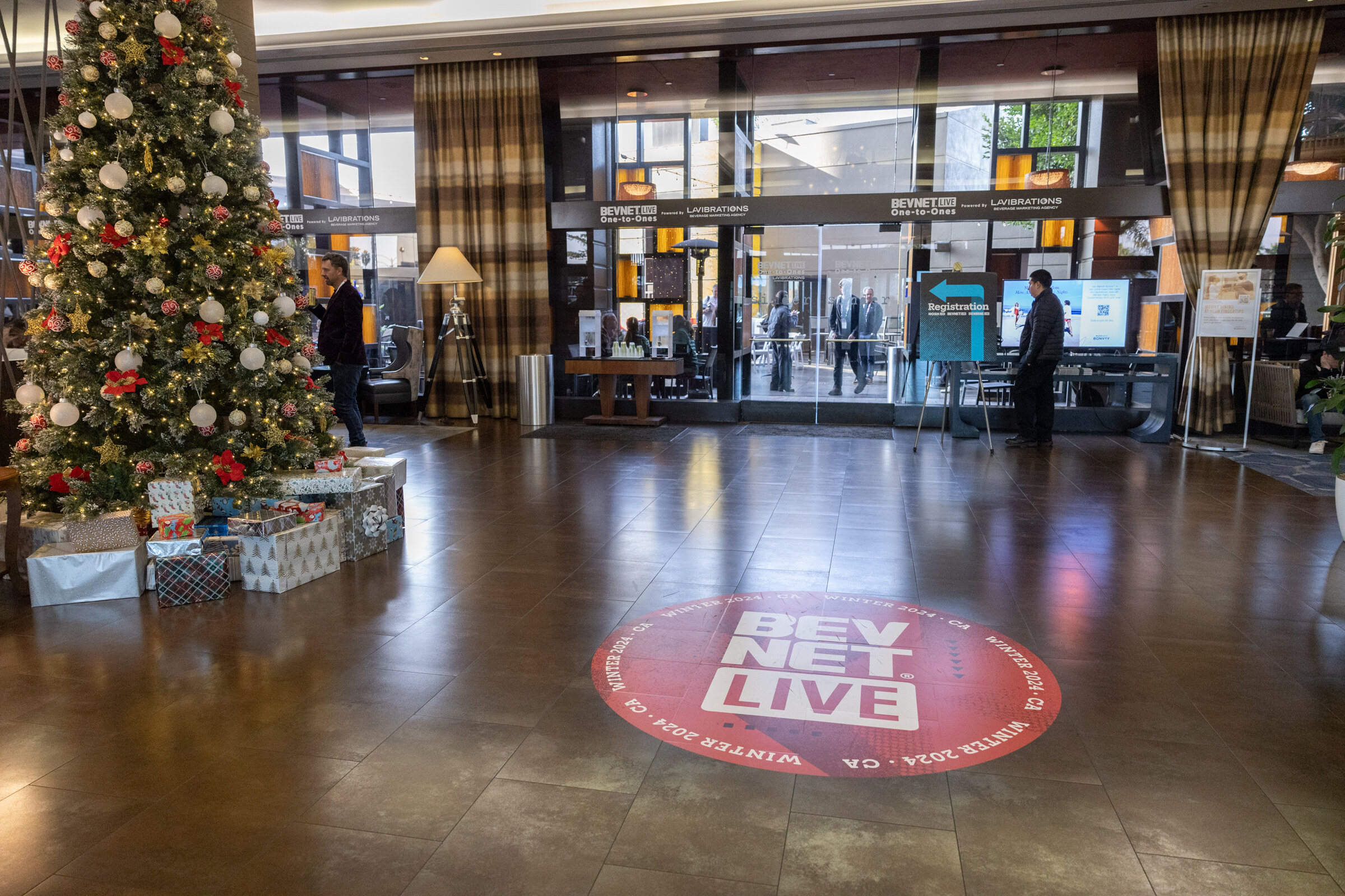 Hotel lobby with a decorated Christmas tree and a red BevNET Live circle on the floor.