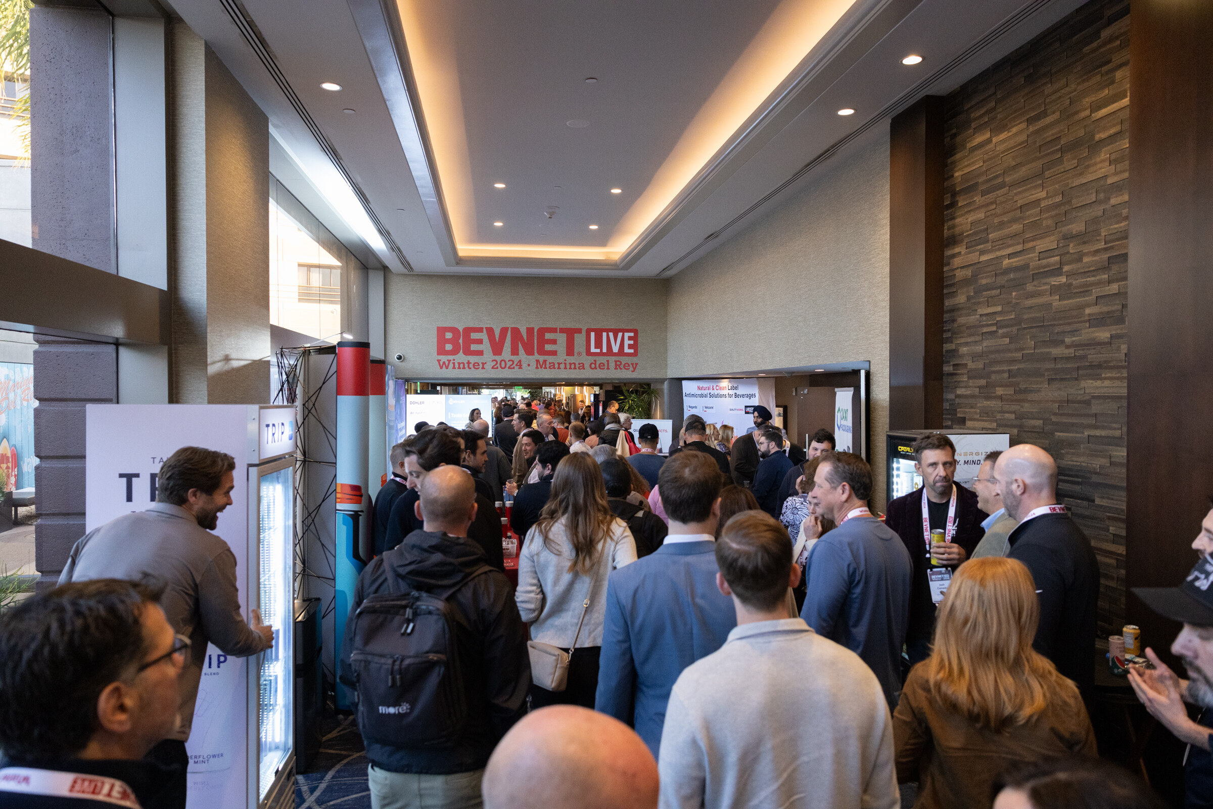 Dense crowd of attendees in a hallway, with a red BevNET Live sign in the background.