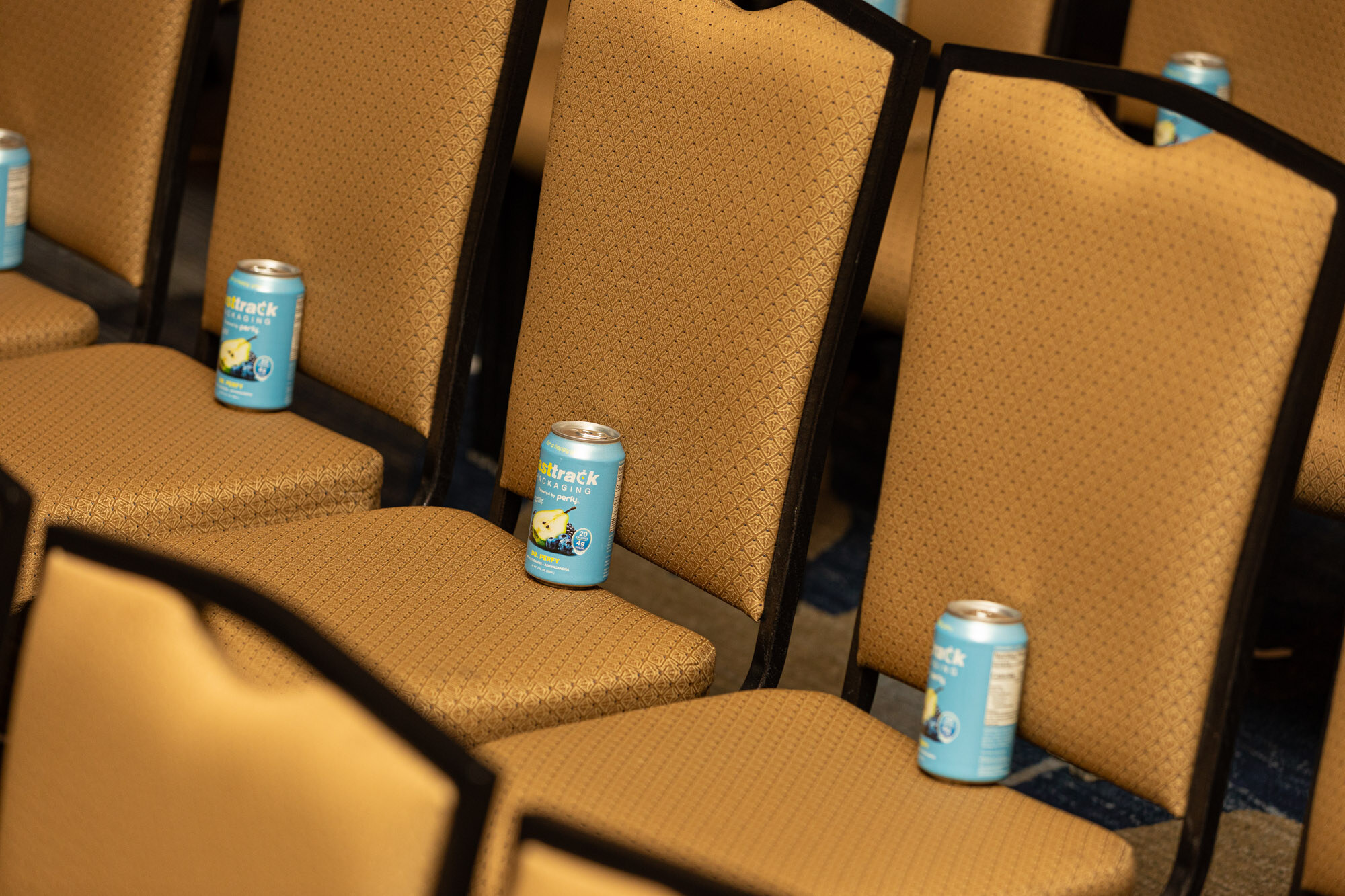 Close-up of gold chairs with blue and yellow cans set on the seats.