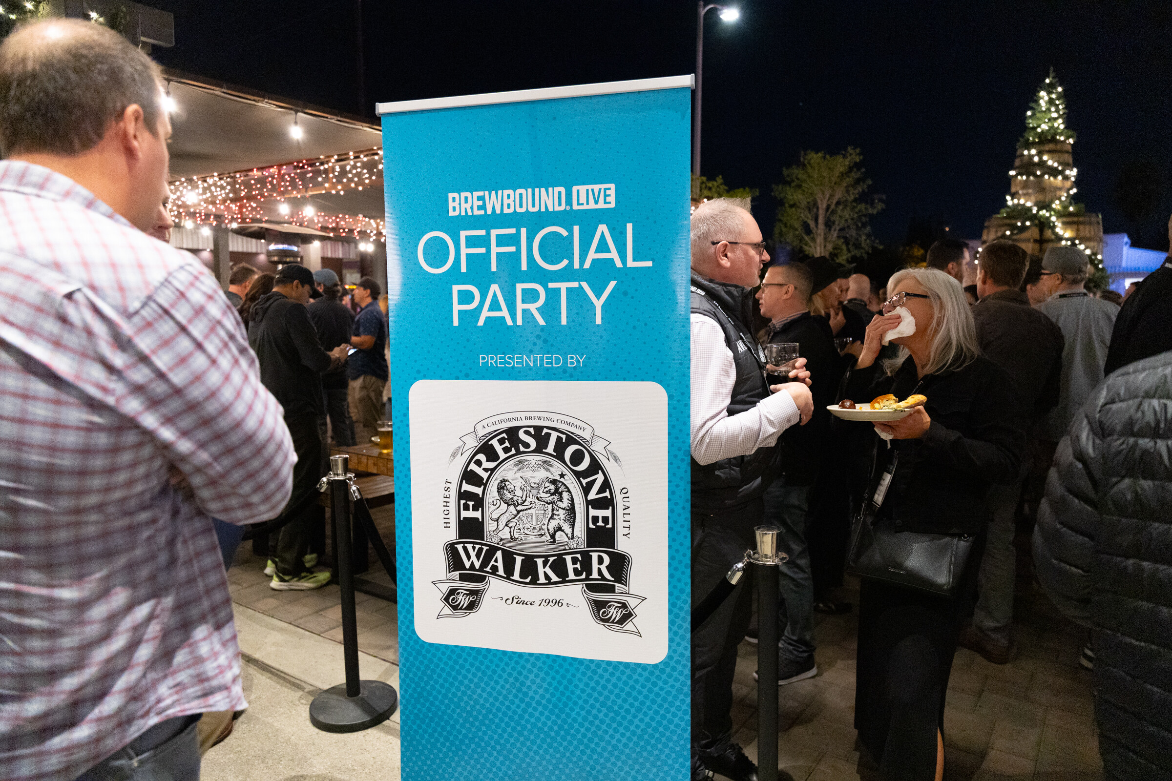 Teal Brewbound Live Official Party banner with a Firestone Walker logo and guests with plates in the background.