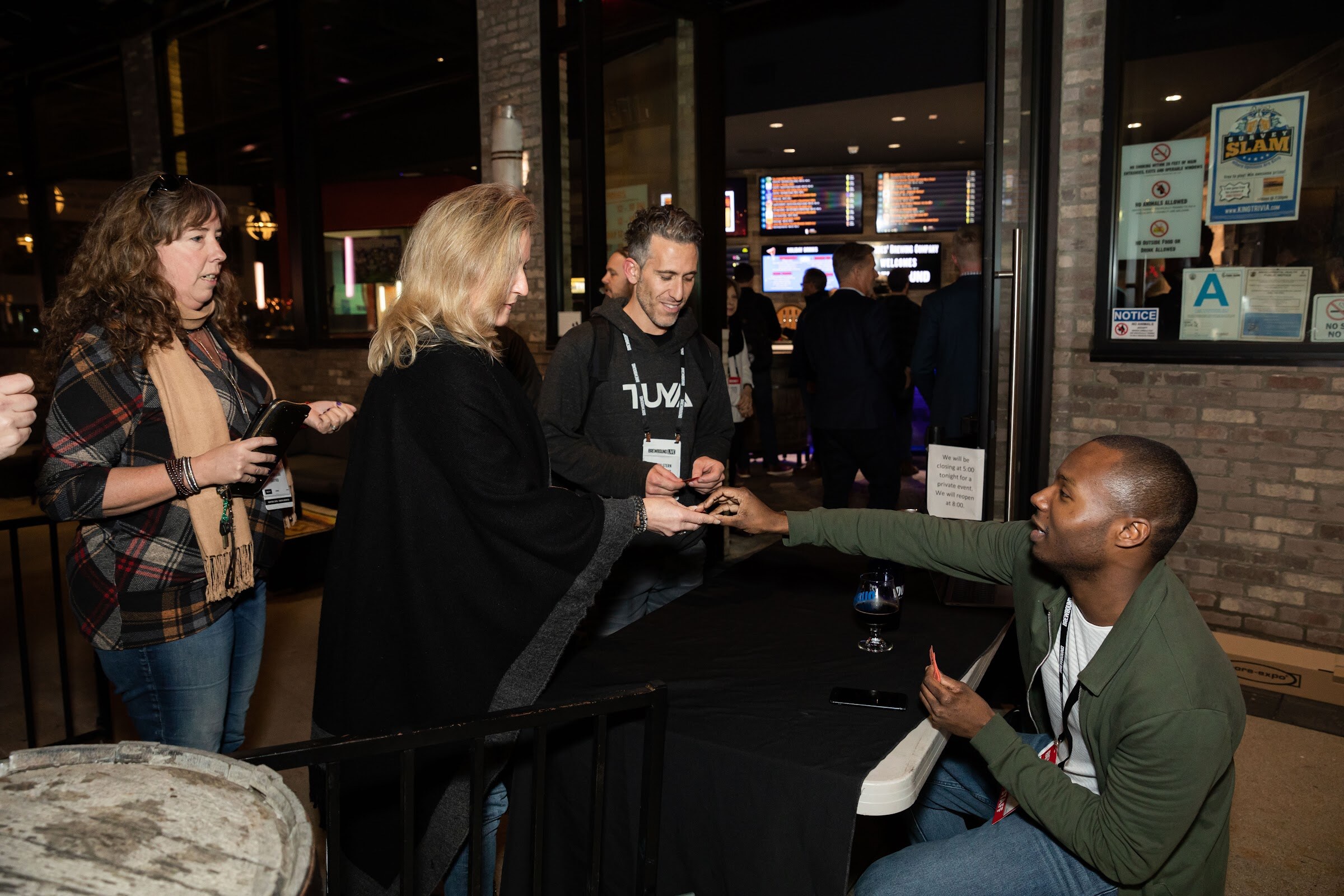 Guests lined up at a table at the entrance while a man in a green jacket checks them in.