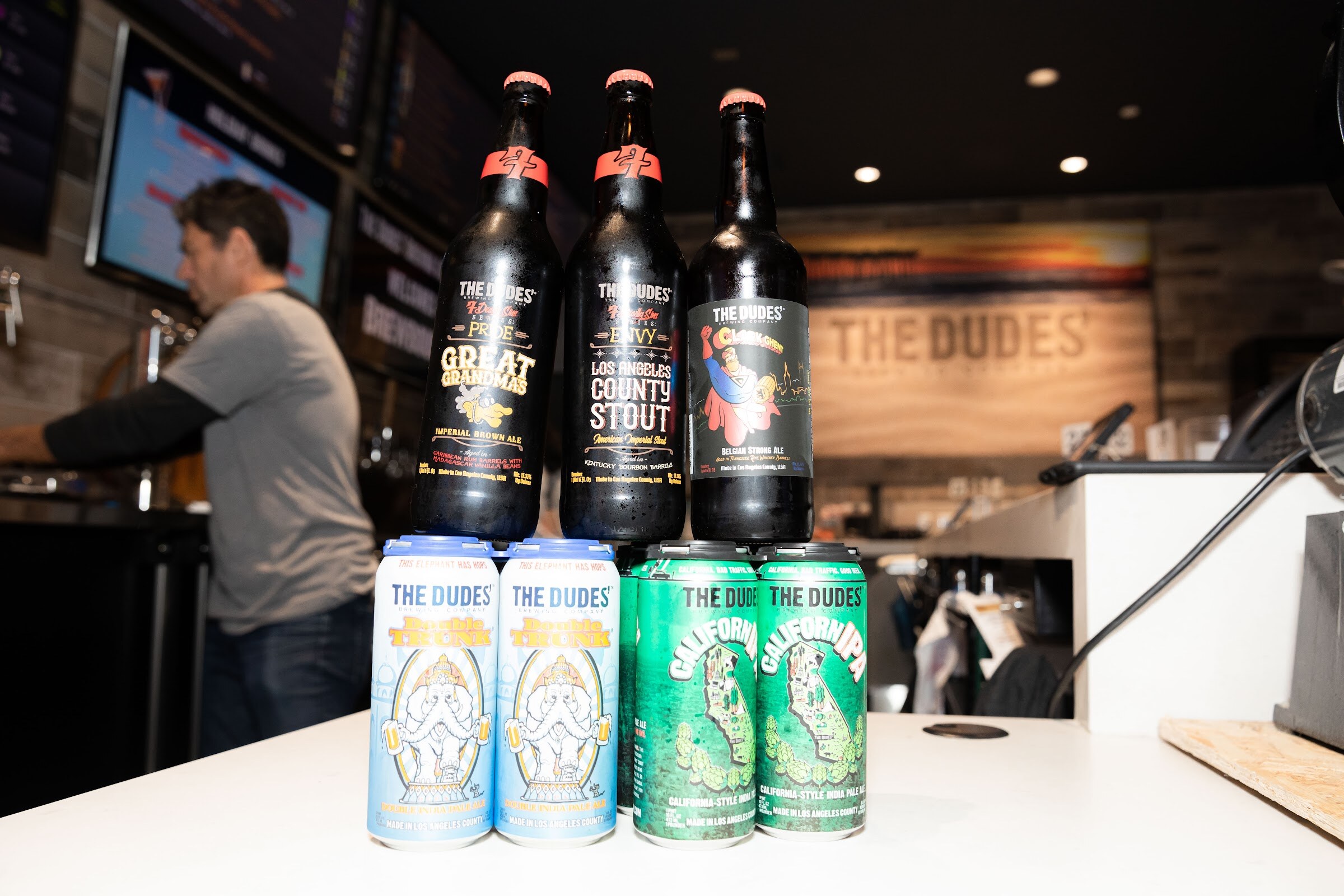 Bar counter with bottles of imperial and Los Angeles stout and cans labelled The Dudes' and California.