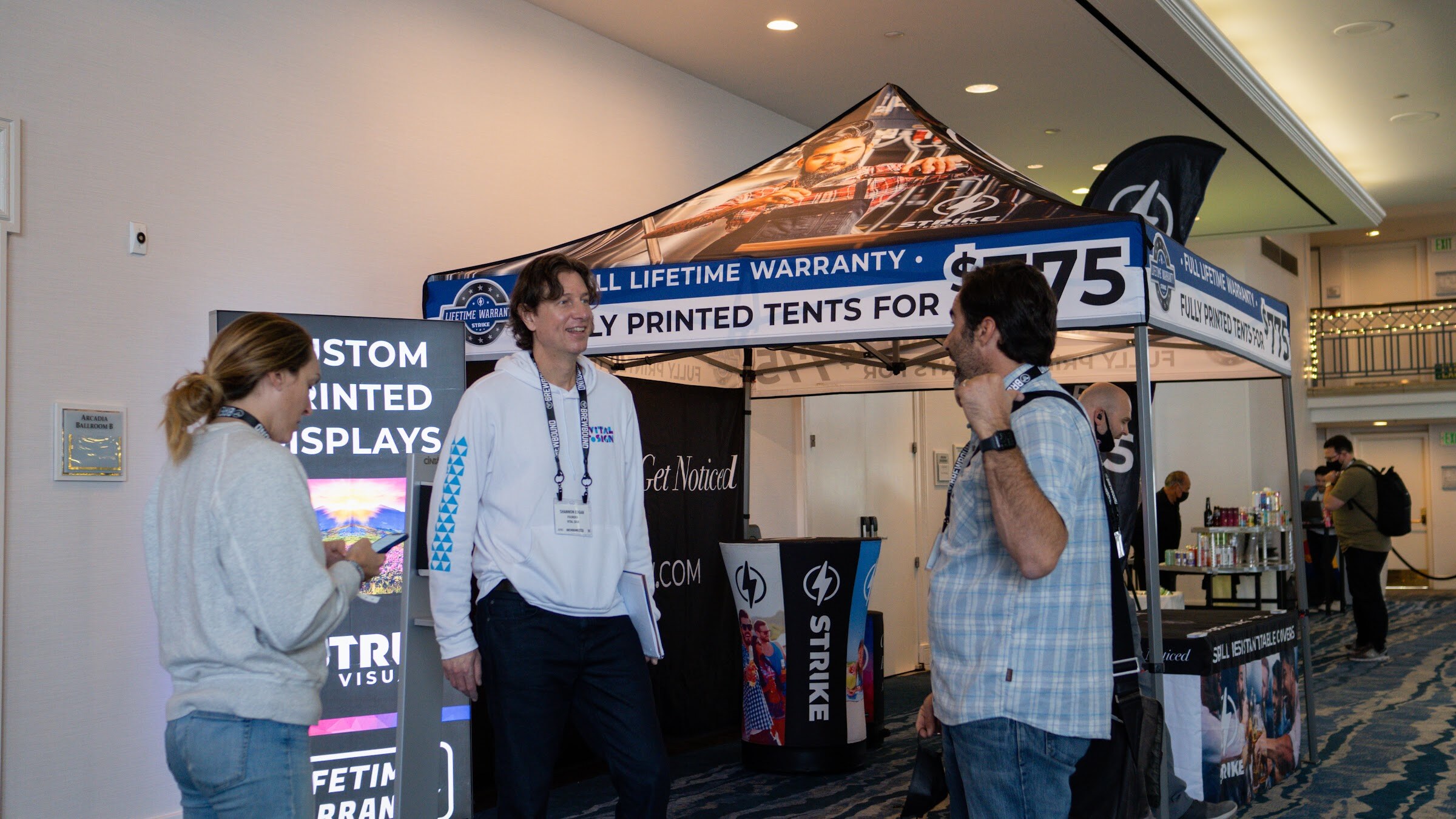 A pop-up tent printed with Full Lifetime Warranty and StrikeNow branding, with three people standing in front.