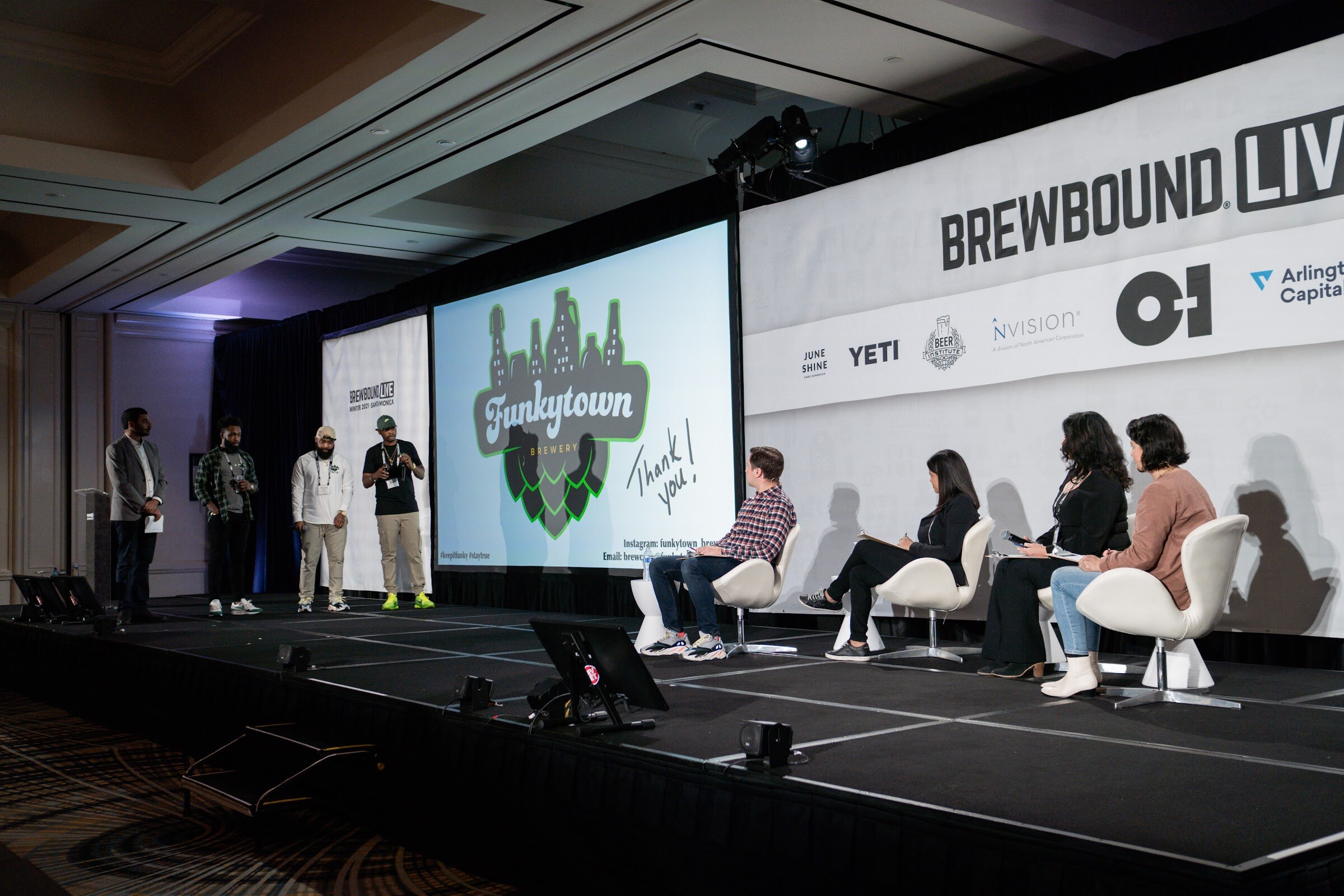 Four team members stand at left on a wide stage beside a Funkytown thank-you slide while four judges sit at right.