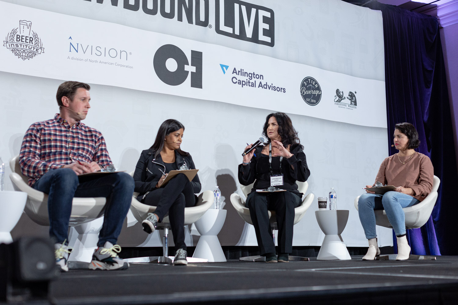 Four judges with clipboards sit in white chairs in front of a Brewbound Live backdrop with sponsor logos.