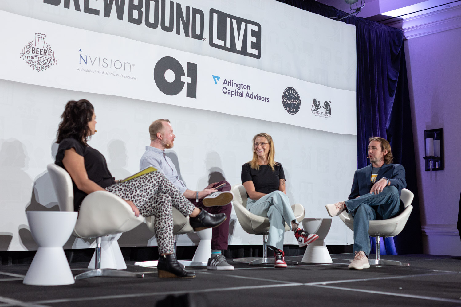 Four people sit in white chairs on a stage under a Brewbound Live banner with sponsor logos.