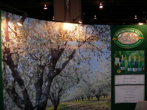 Booth graphic of a blossoming orchard reading Sonoma Sparkler, with a green Sonoma Cider Mill panel from Healdsburg, California showing bottles.