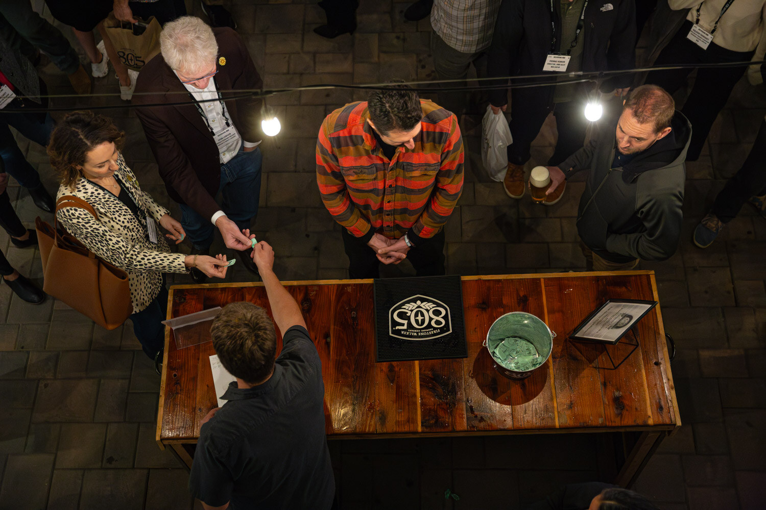 An overhead view of guests around a wooden bar table with a 508 logo sign and a bucket.