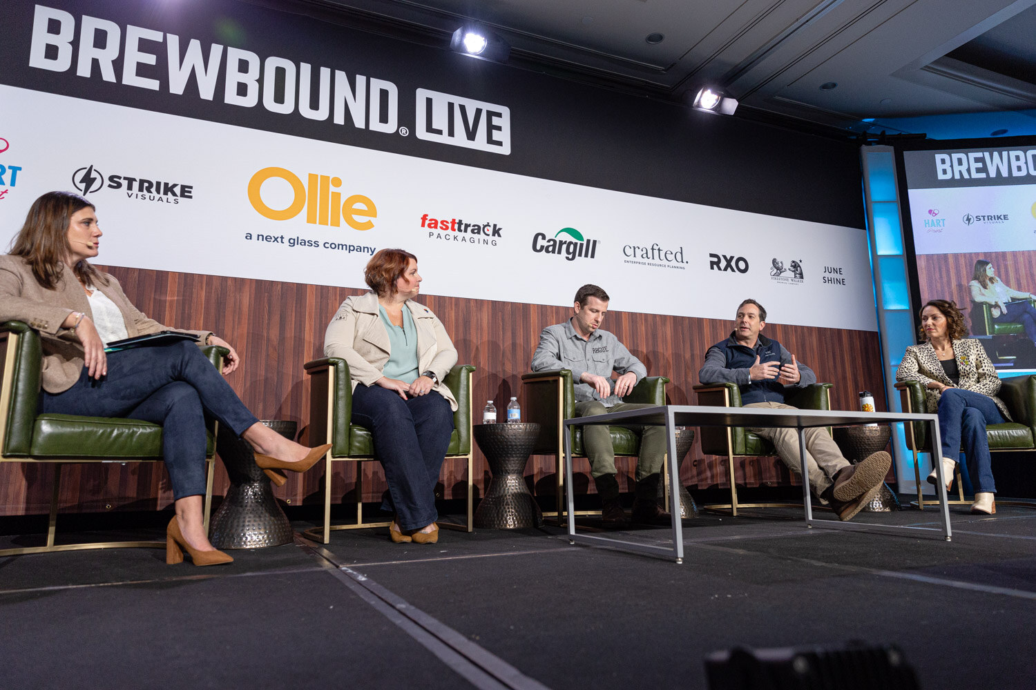 Five people sit in green armchairs on a stage under a Brewbound Live banner with sponsor logos including Ollie and Cargill.