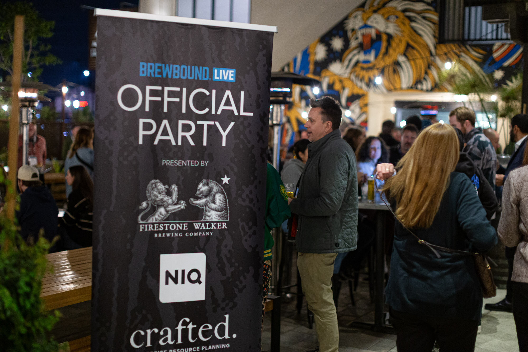 A standing banner reads Brewbound Live Official Party, presented by Firestone Walker with NIQ and crafted, with a lion mural behind.