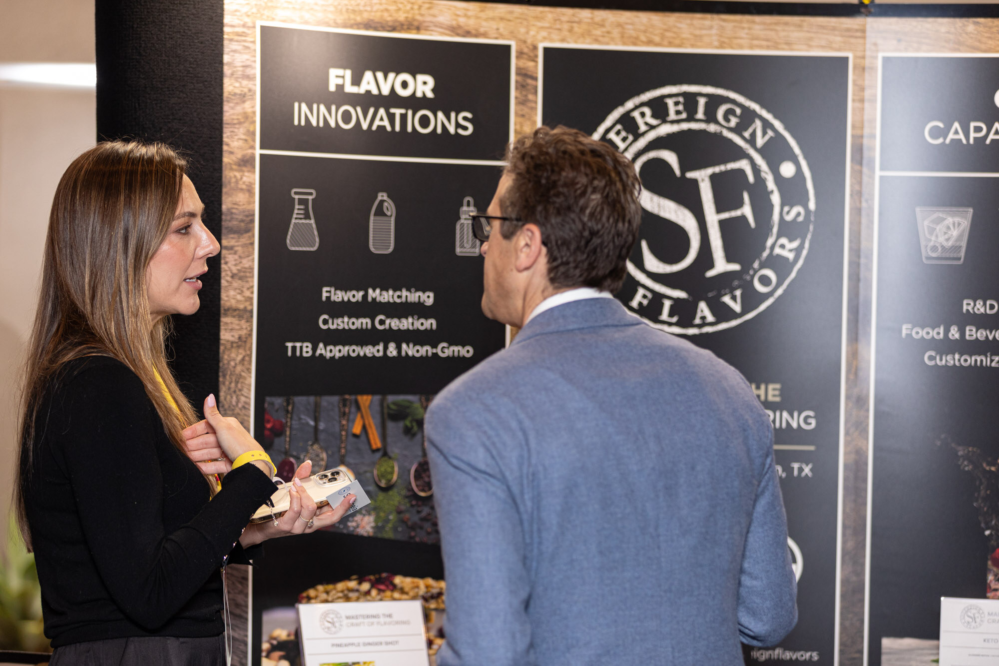 A woman and a man talk in front of a Sovereign Flavors banner about flavor innovations.