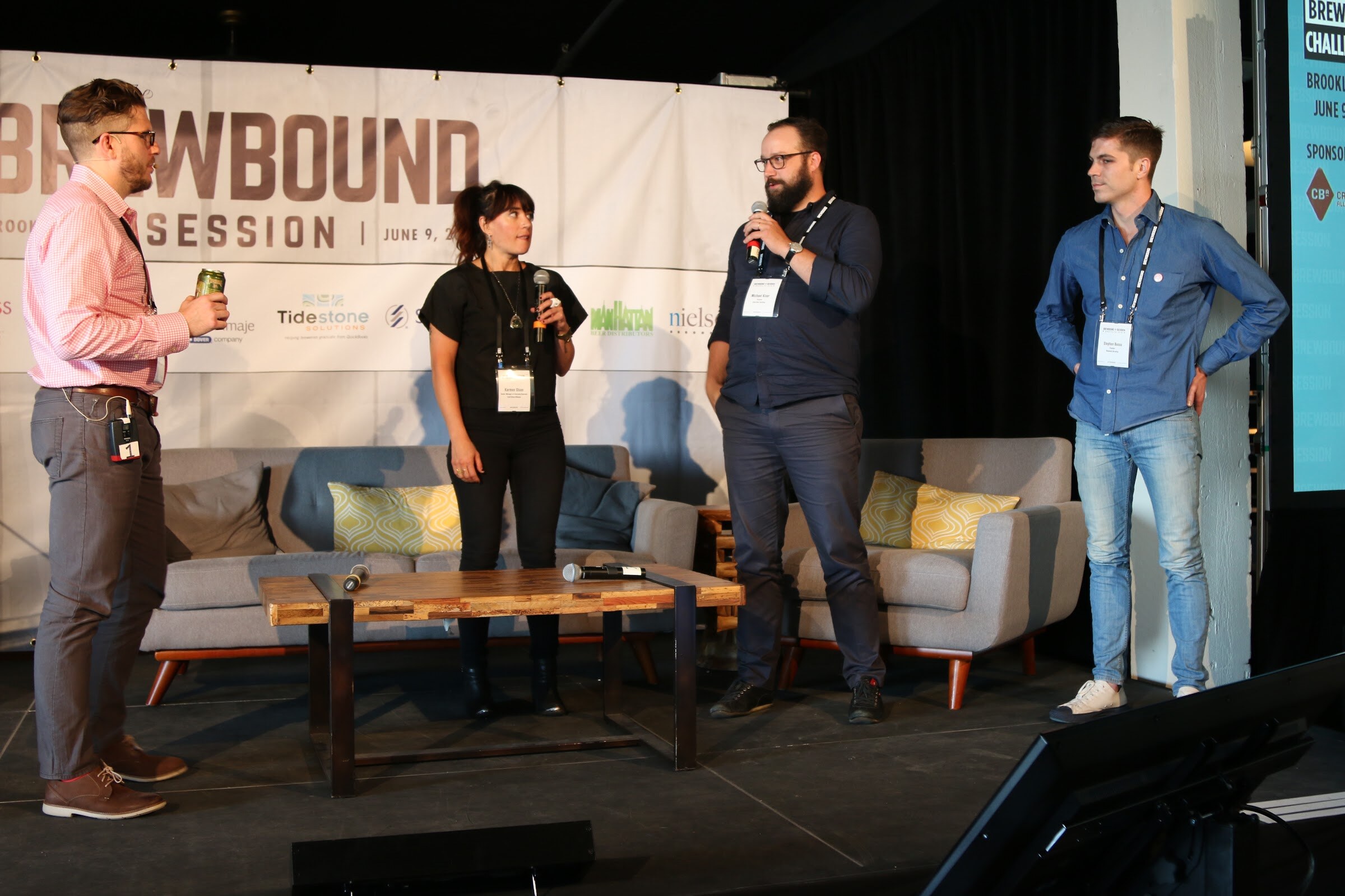 Four people standing on stage, two holding microphones, with a Brewbound Session banner and a Startup Brewery Challenge panel behind them.