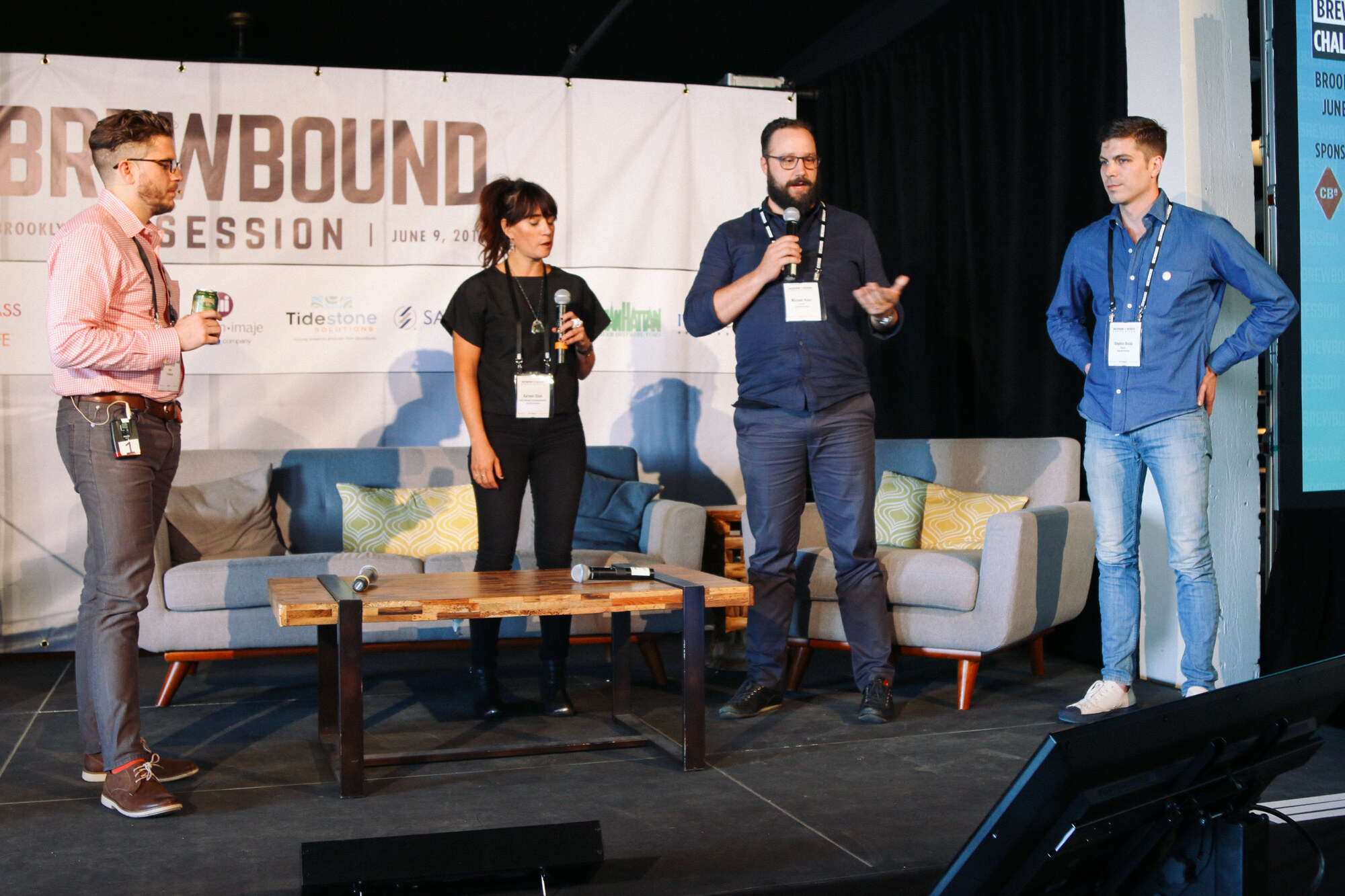 Four people standing on a stage with couches and a coffee table, with a Brewbound Session banner and a teal Startup Brewery Challenge panel at right.