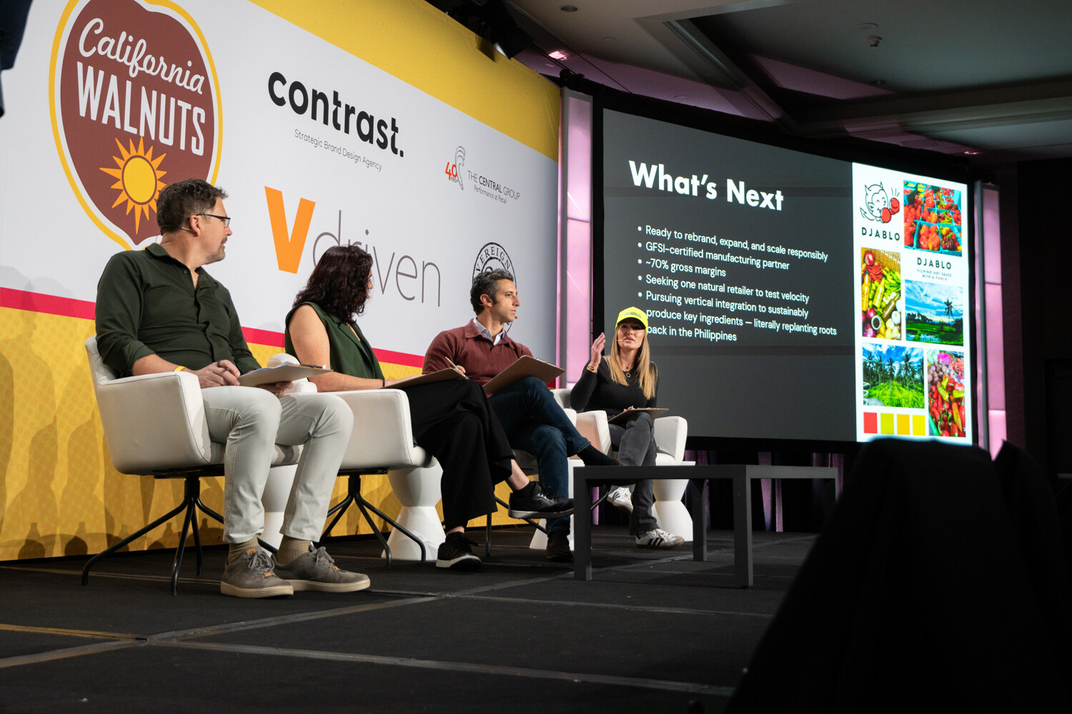 Four judges seated on stage in front of a screen showing a slide titled What's Next with a Djablo logo.