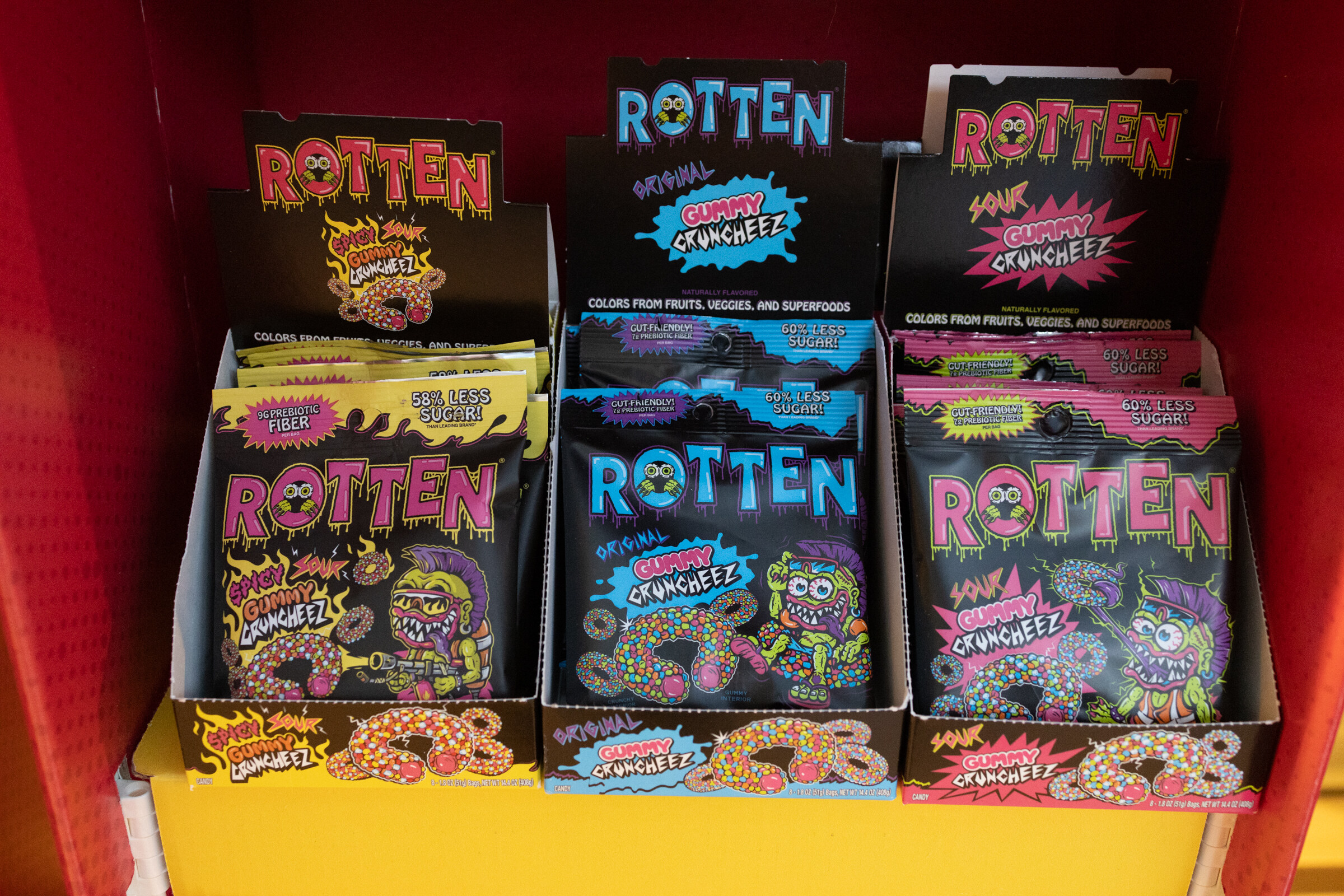 Three boxes of Rotten gummy candy packages stacked in a red display.