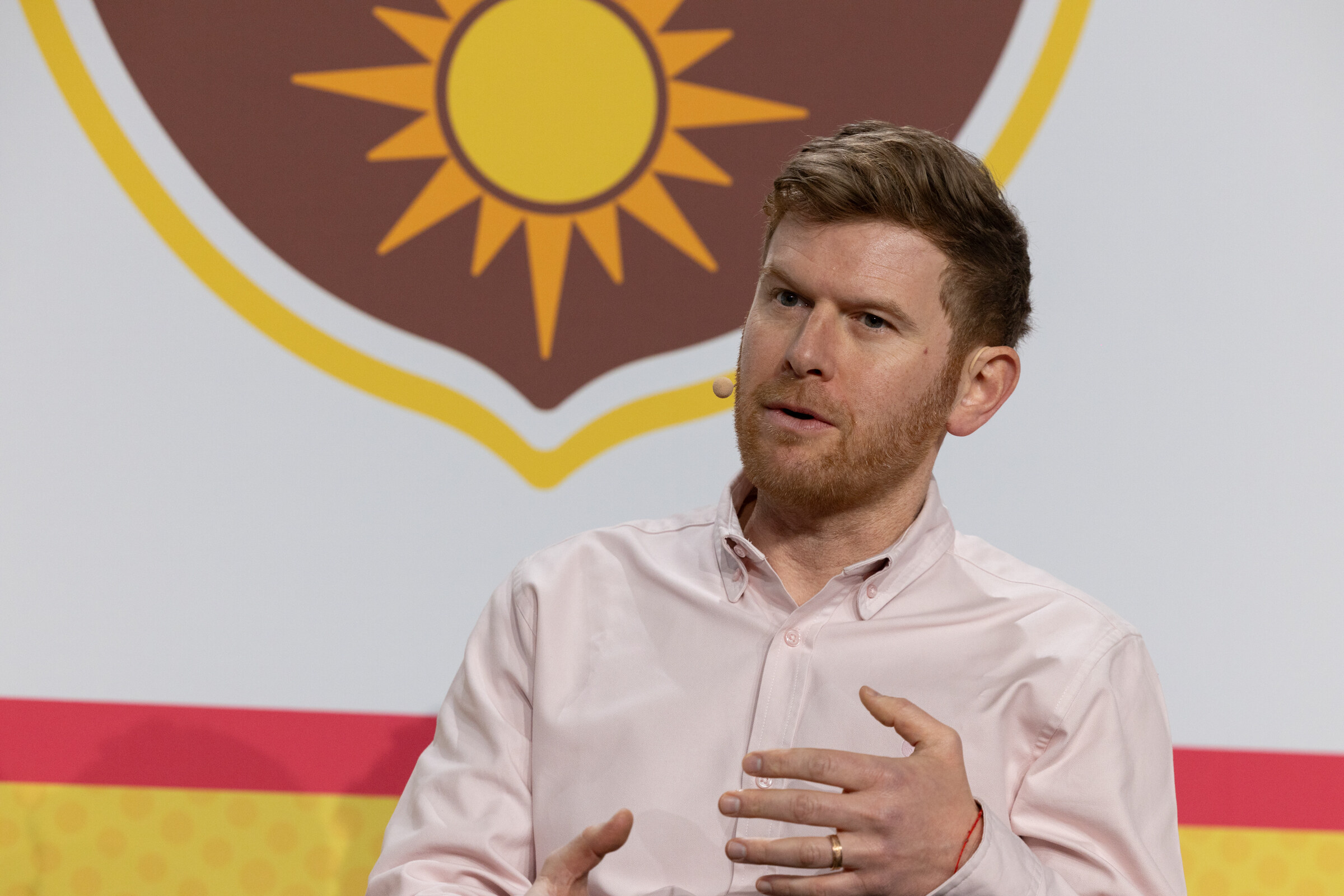 A man in a pink button-down shirt speaking and gesturing in front of a California Walnuts logo.