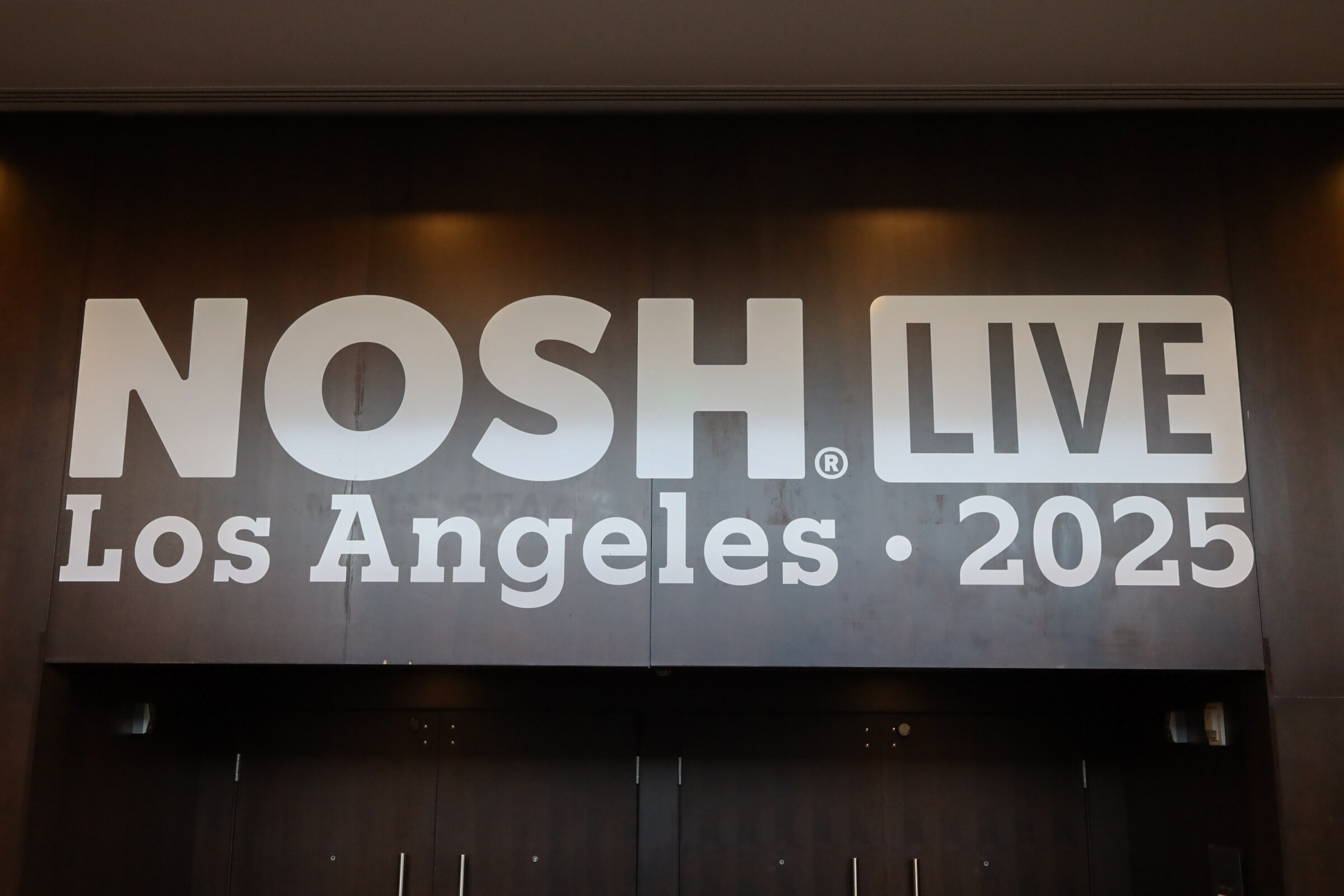 A gray illuminated wall sign reading Nosh Live Los Angeles 2025.