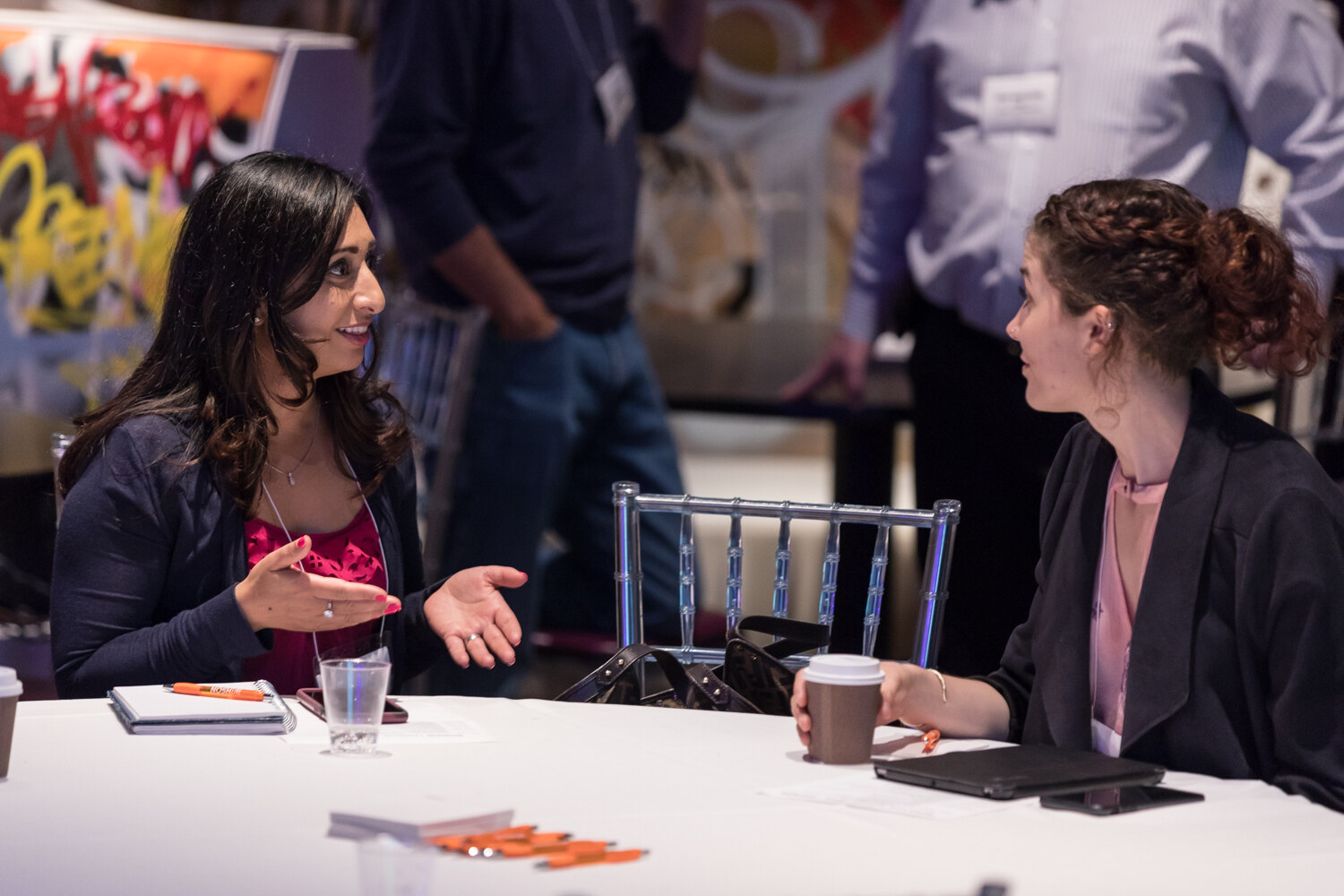 Two women talk over coffee at a round table during Boot Camp networking.