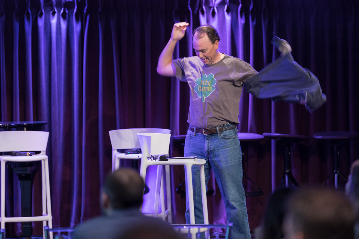 Investors session presenter removes a jacket on stage to reveal a graphic t-shirt.