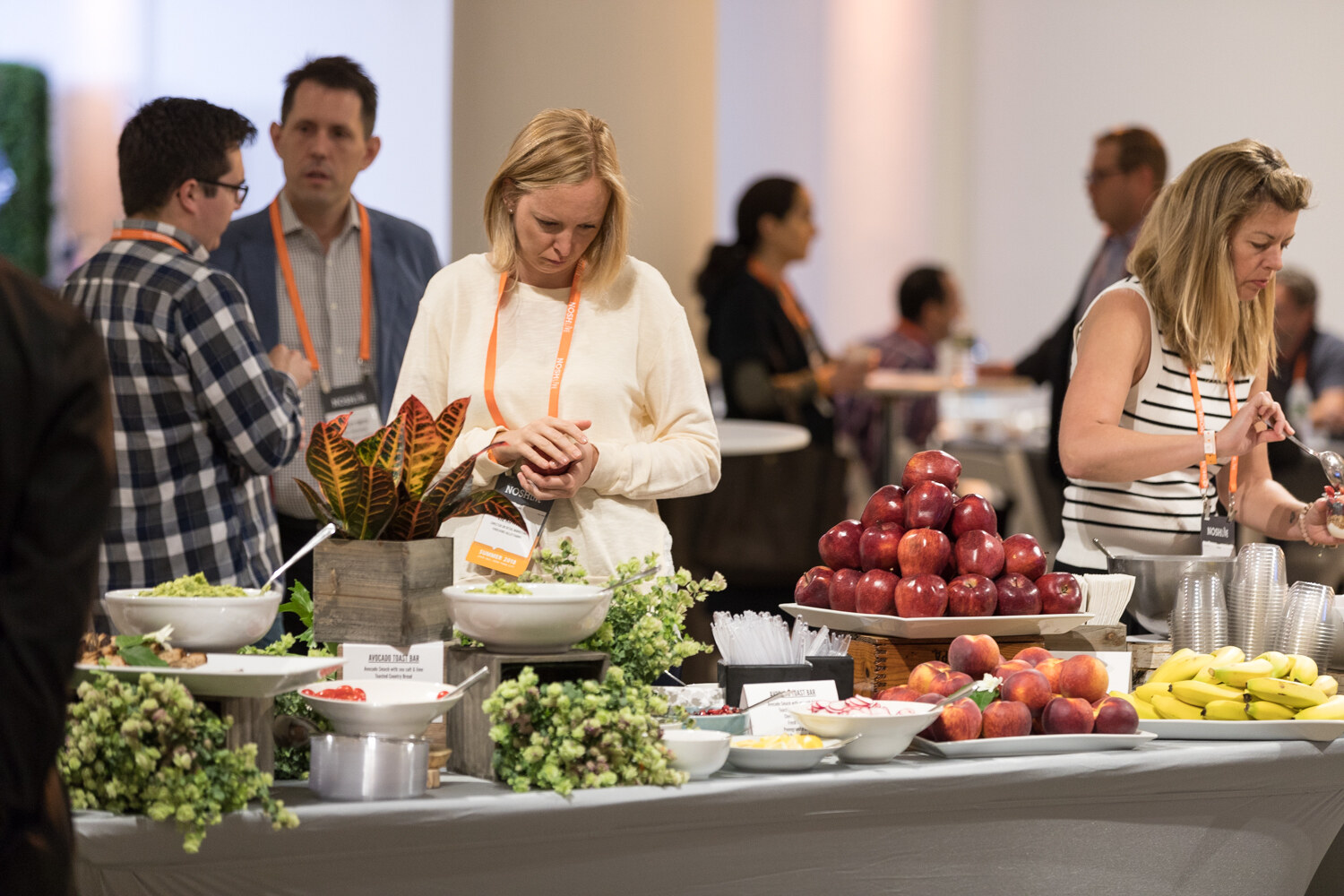 A breakfast buffet of fresh fruit and greenery as attendees fill plates before the morning program.