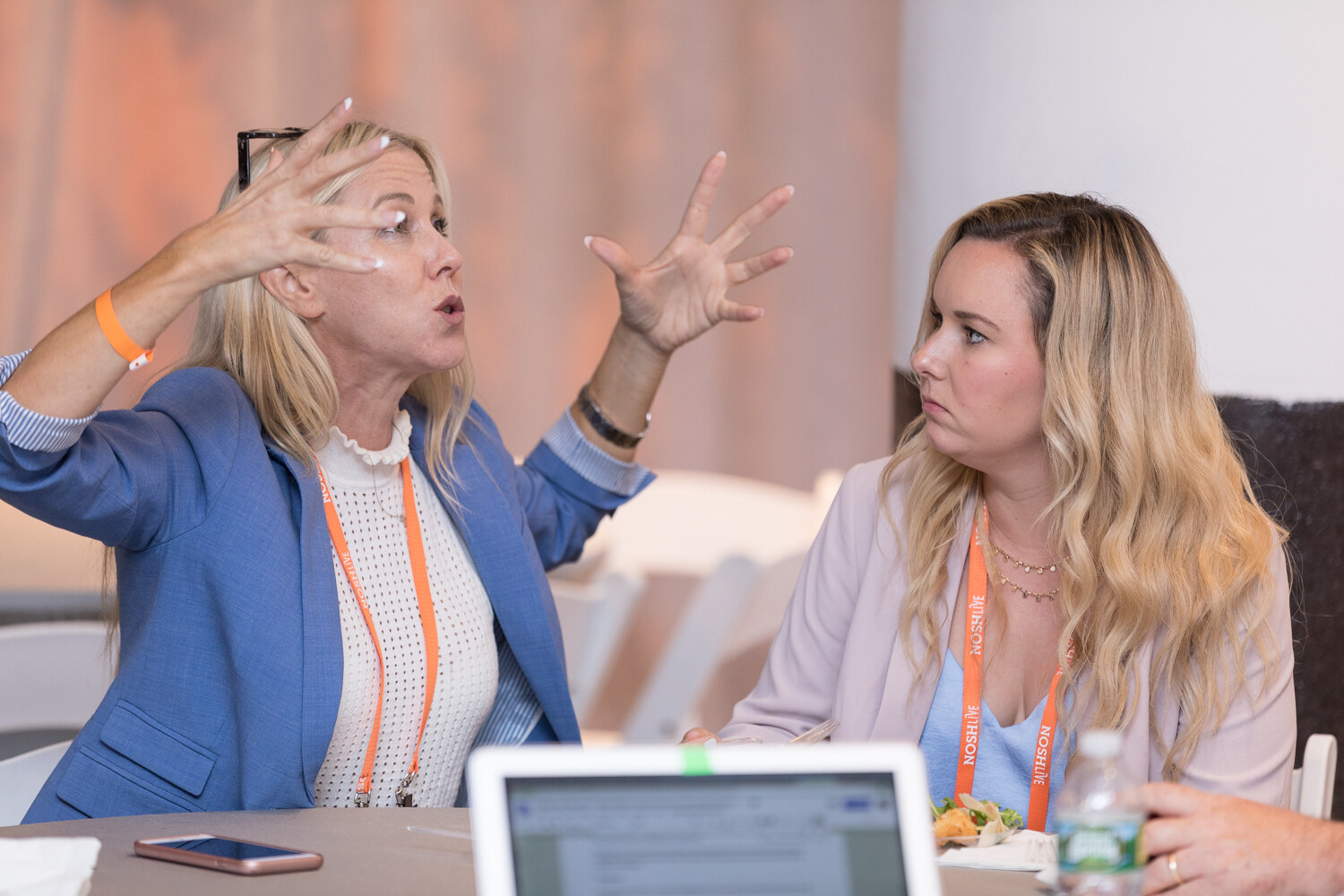 Two women talk animatedly at a table with a laptop during the networking lunch.