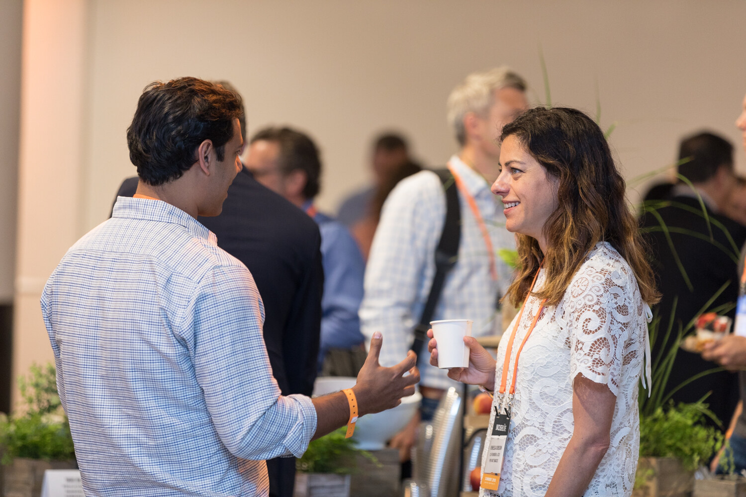 A man and a woman in a white lace top talk during the morning networking break.