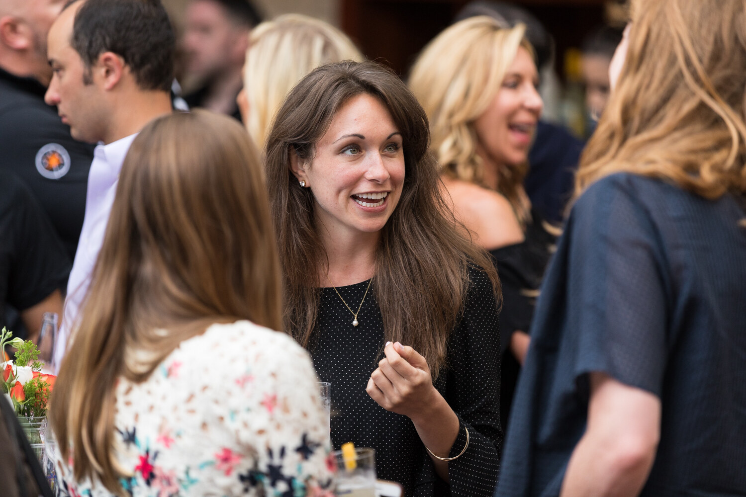 A woman in a black top talks animatedly with other guests at the Nosh Live afterparty.