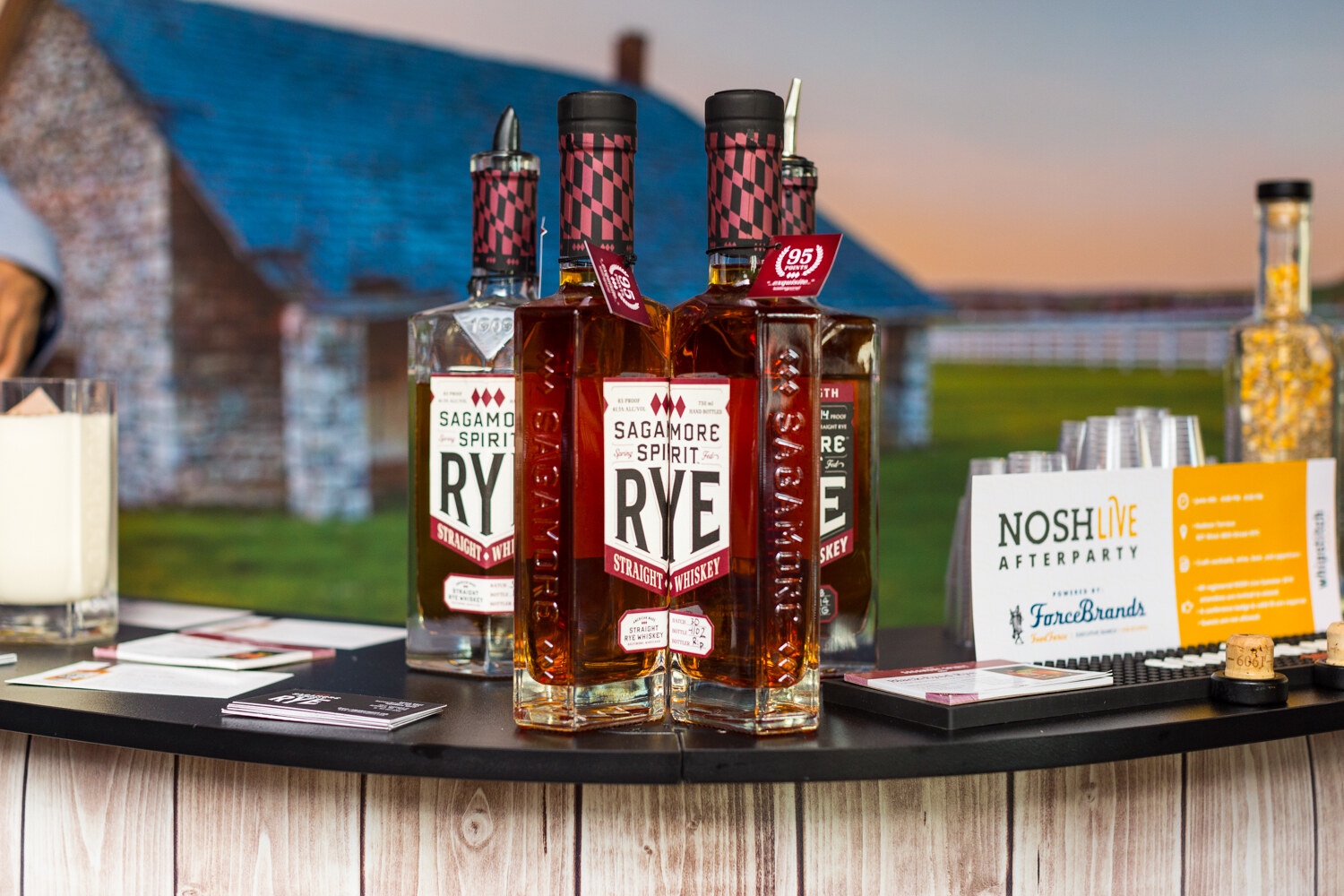 Bottles of Sagamore Spirit Rye on a bar display beside a NOSH LIVE Afterparty card.