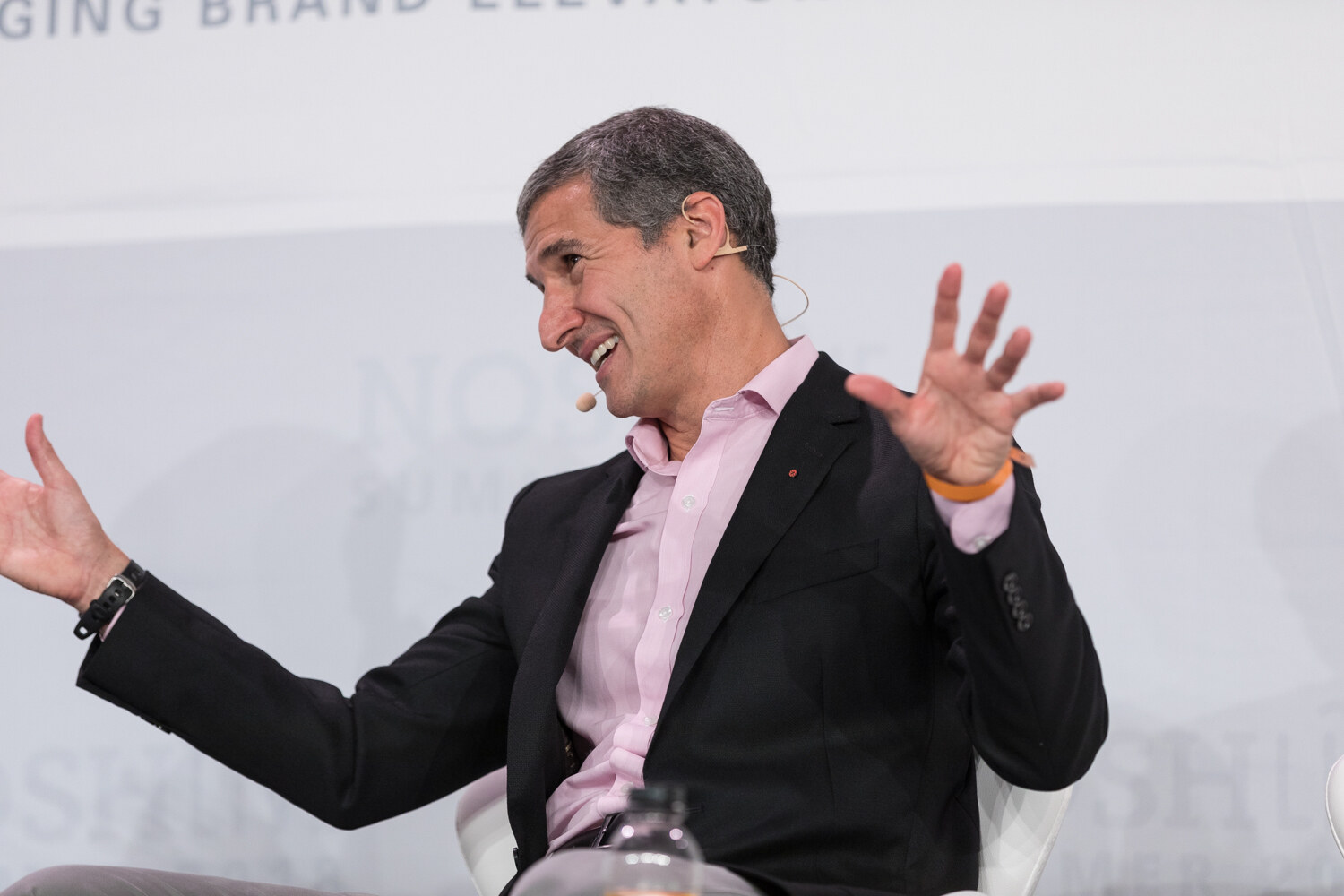 A guest laughs and gestures broadly while seated on stage during the Leadership Notes from the Chairman and TeaEO session.
