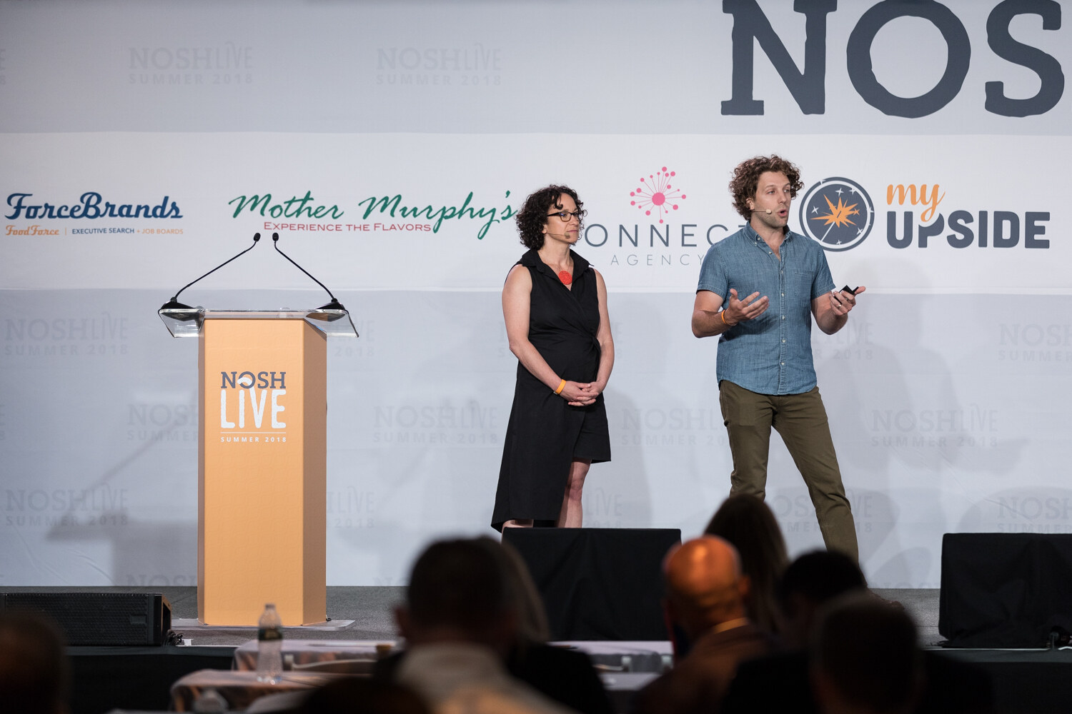 Two presenters on stage beside the NOSH LIVE lectern during The Move to Meaning: Product Becomes Brand session.