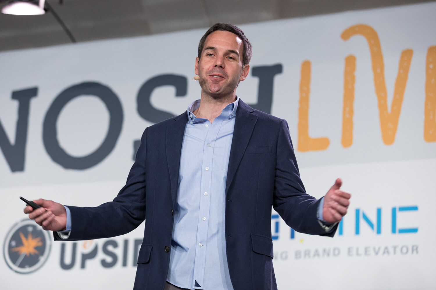 A presenter in a navy blazer gestures in front of the NOSH LIVE backdrop during the Strategic Profile session.