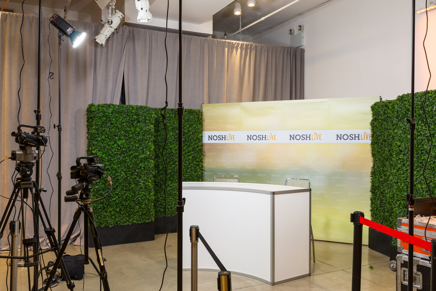 The Nosh Live livestream studio set with a white desk, ivy panels and video cameras before the event.