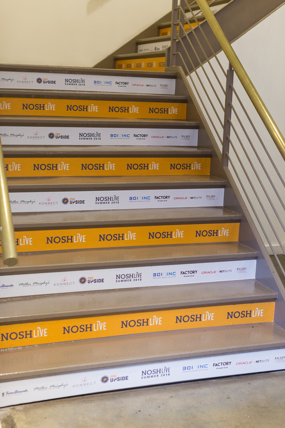 A stairway with NOSH LIVE and sponsor logos printed on each step riser.