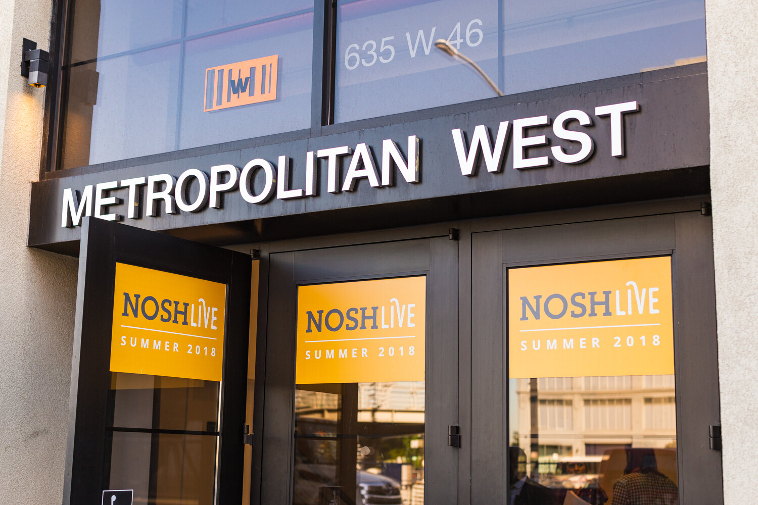The Metropolitan West entrance at 635 W 46th Street with NOSH LIVE Summer 2018 posters in the doors.