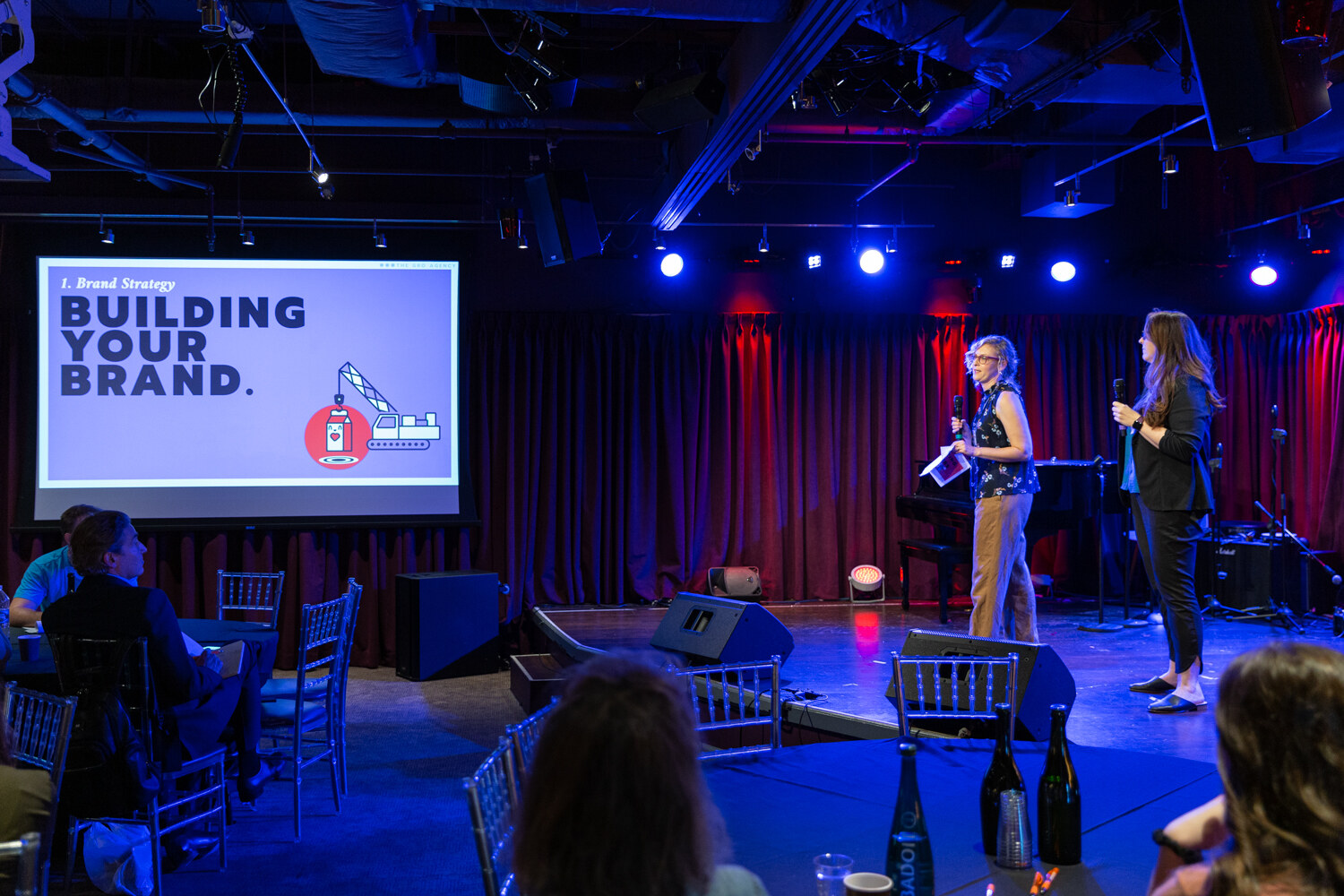 Two Boot Camp presenters on stage beside a Building Your Brand slide