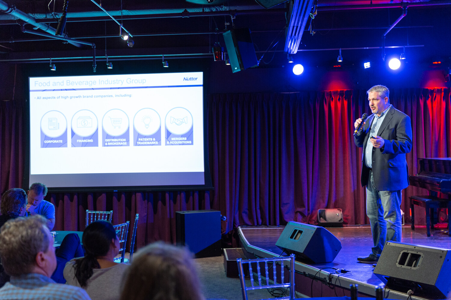 Boot Camp speaker in a navy blazer on stage beside a slide titled Food and Beverage Industry Group