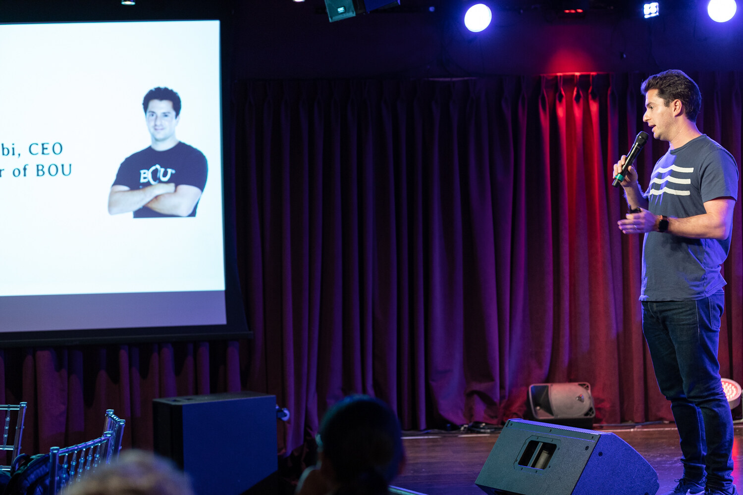 Boot Camp speaker beside a projected slide showing a photo of a man in a BOU T-shirt
