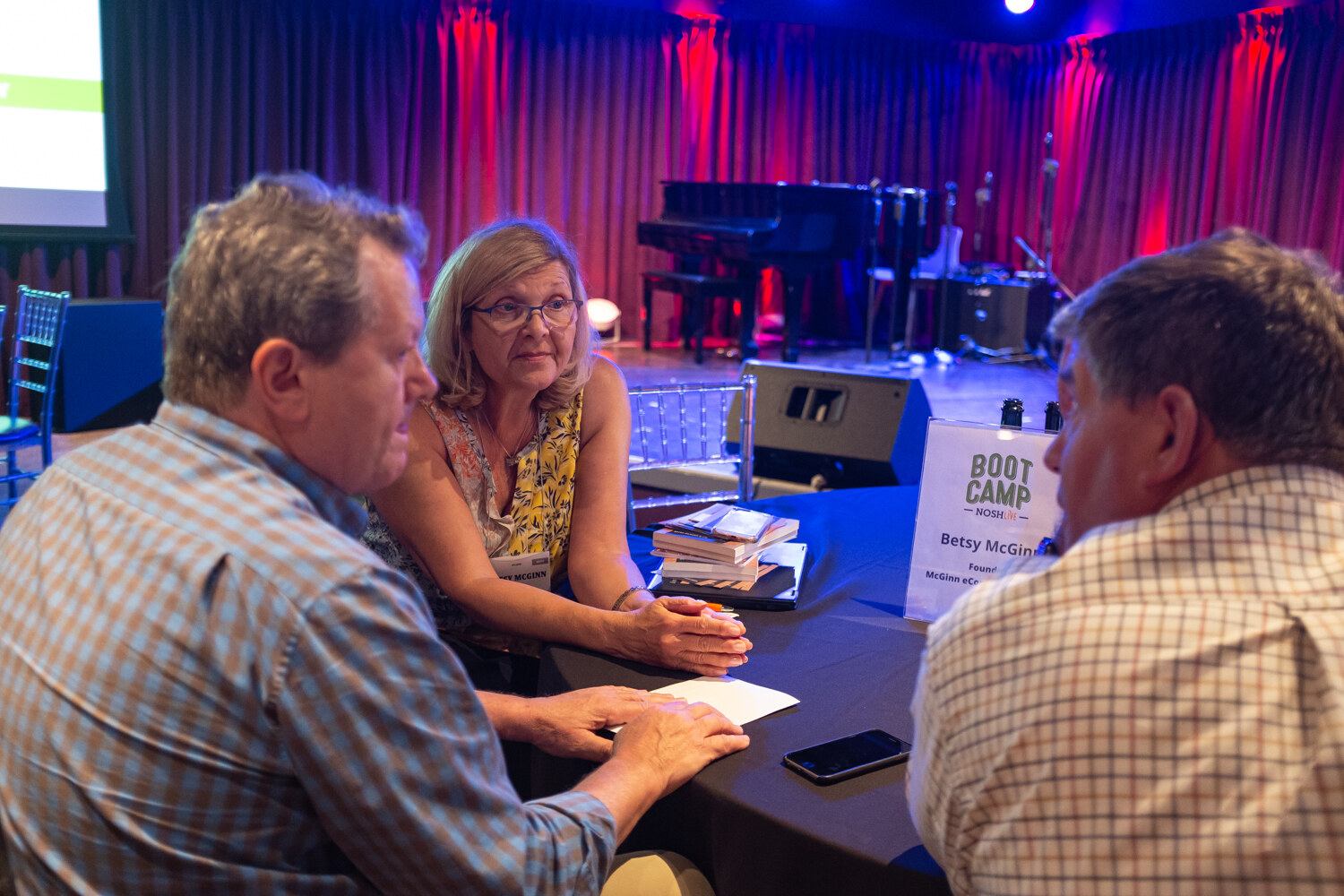 Attendees in conversation around a Boot Camp mentor table with a table sign