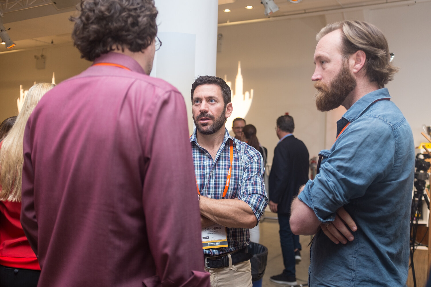 Three men talking in the networking hall, one in a plaid shirt and one with a beard