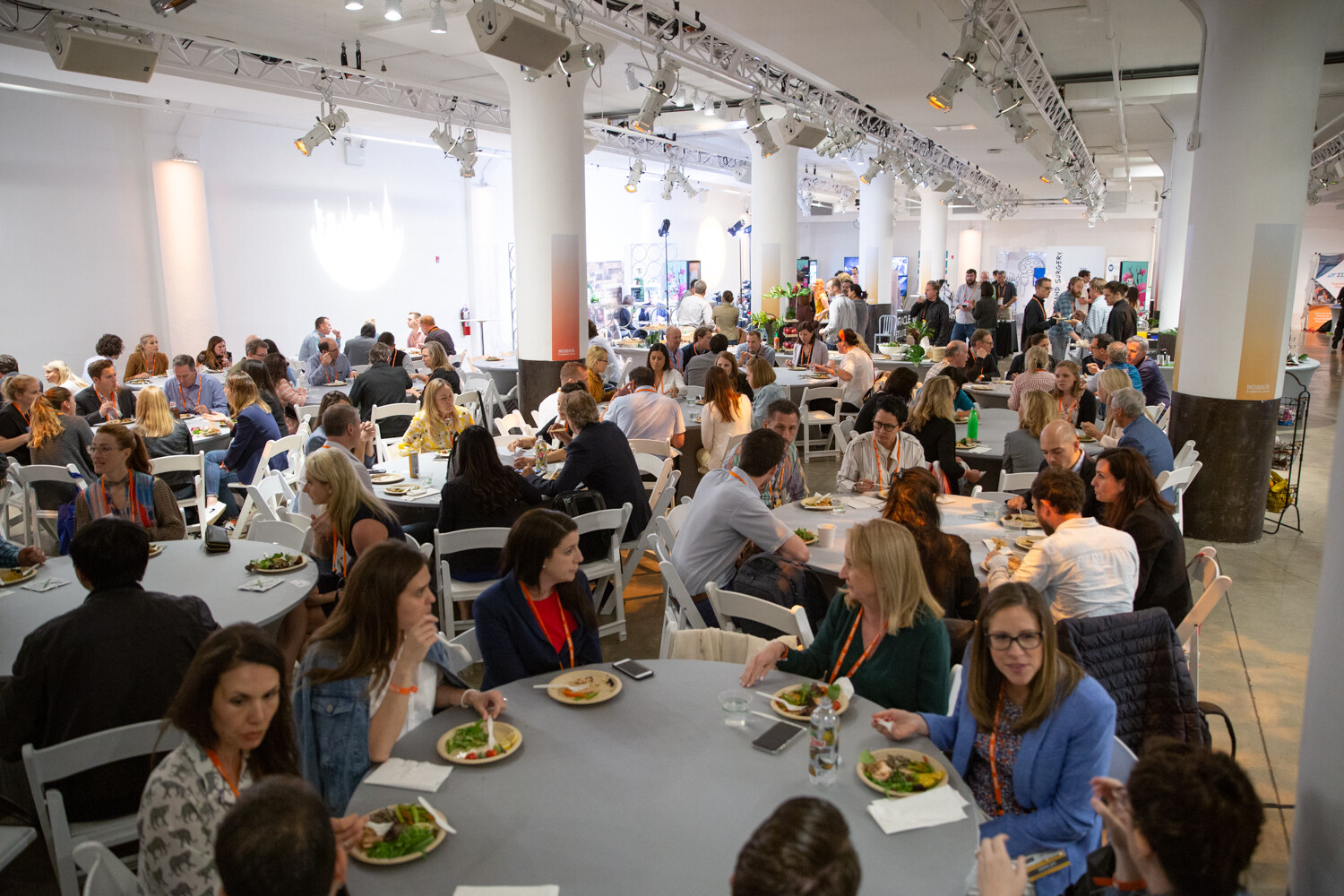 Packed lunch hall seen from above with attendees at round tables