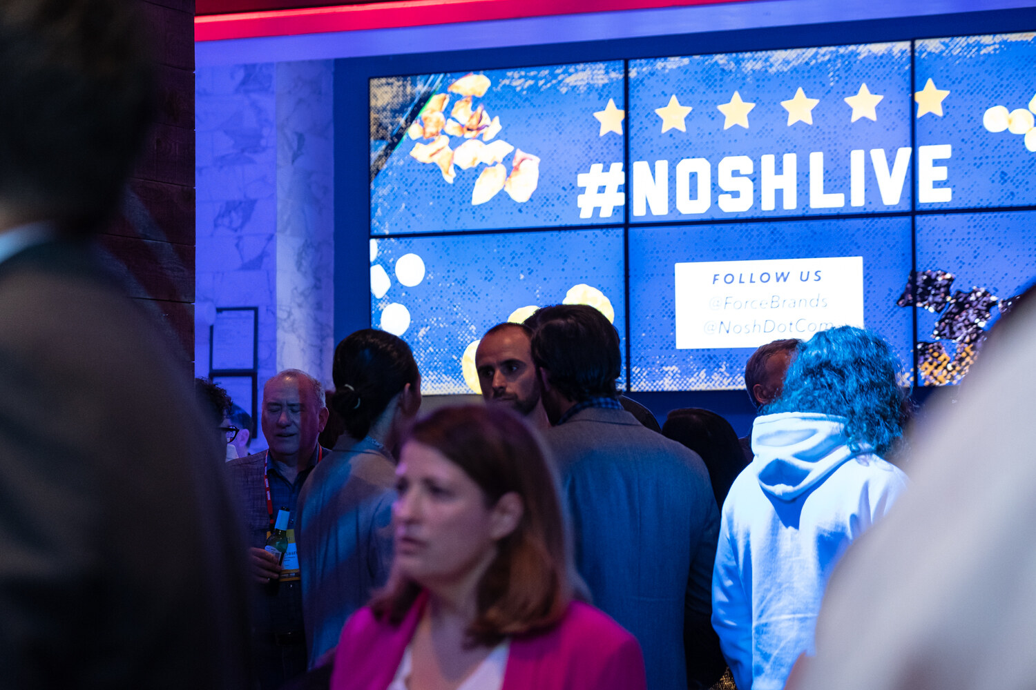 Guests gathered beneath the #NOSHLIVE video wall behind the bar