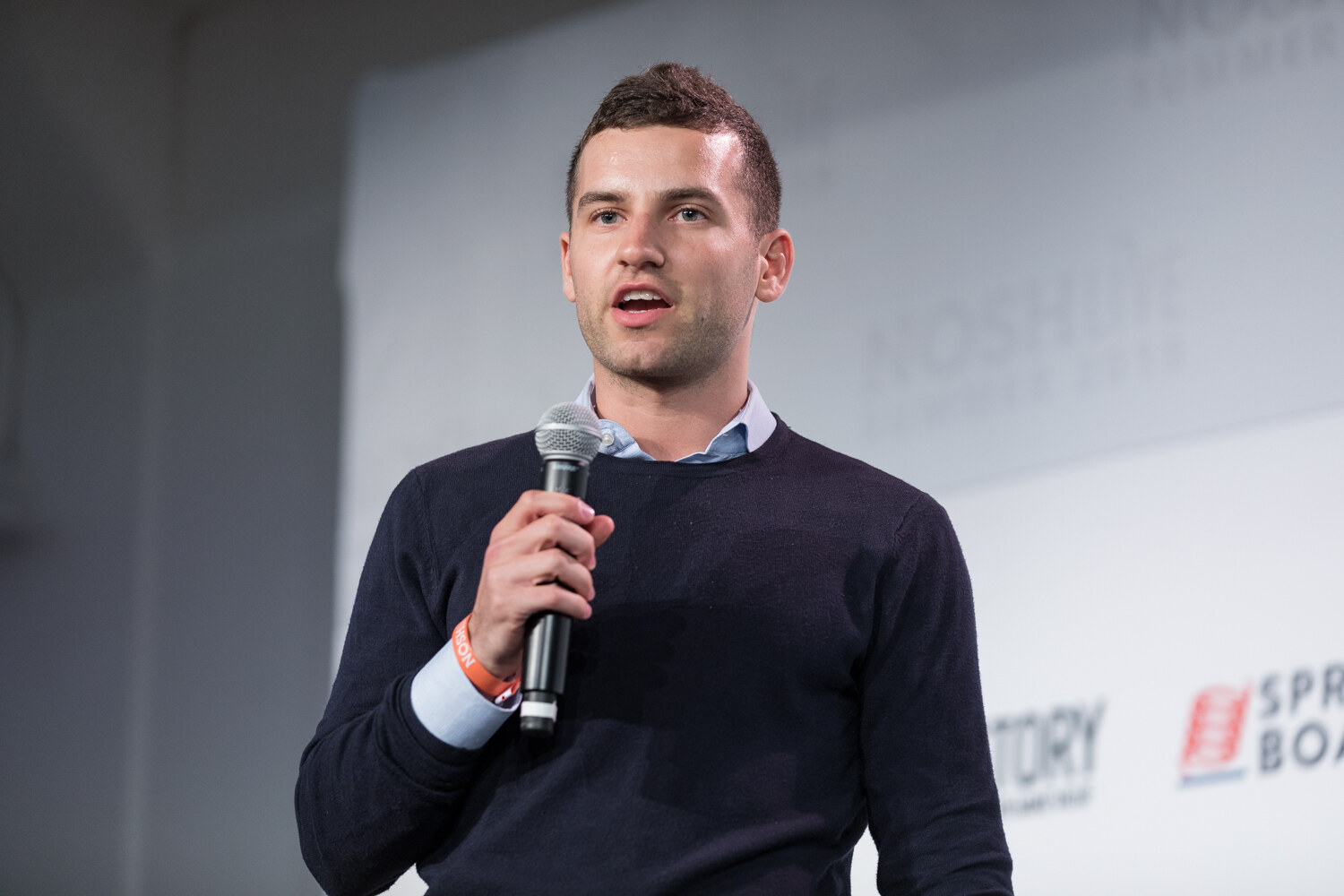 Pitch Slam presenter in a navy sweater pitching with a microphone