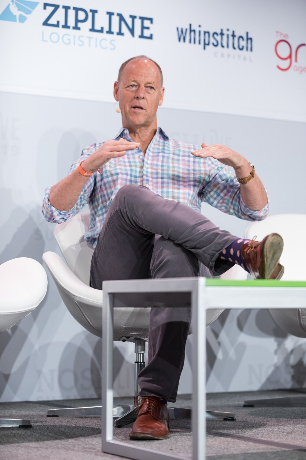 Man in a pastel checked shirt gesturing with open hands, portrait view