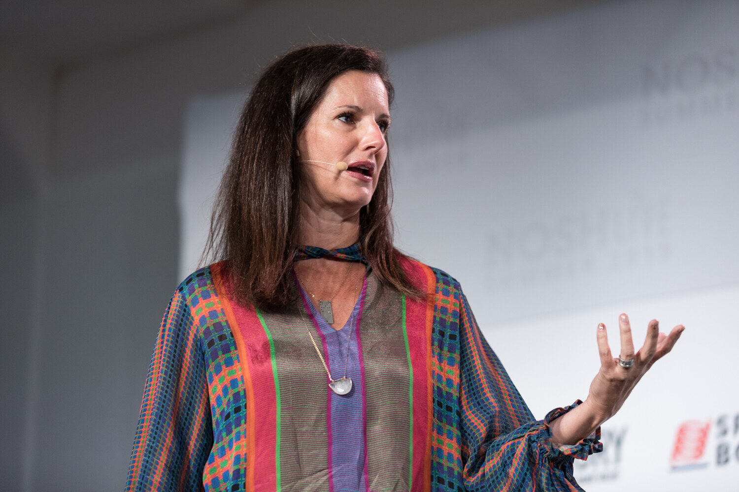 Woman in a multicolor striped blouse gesturing with an open hand in close view