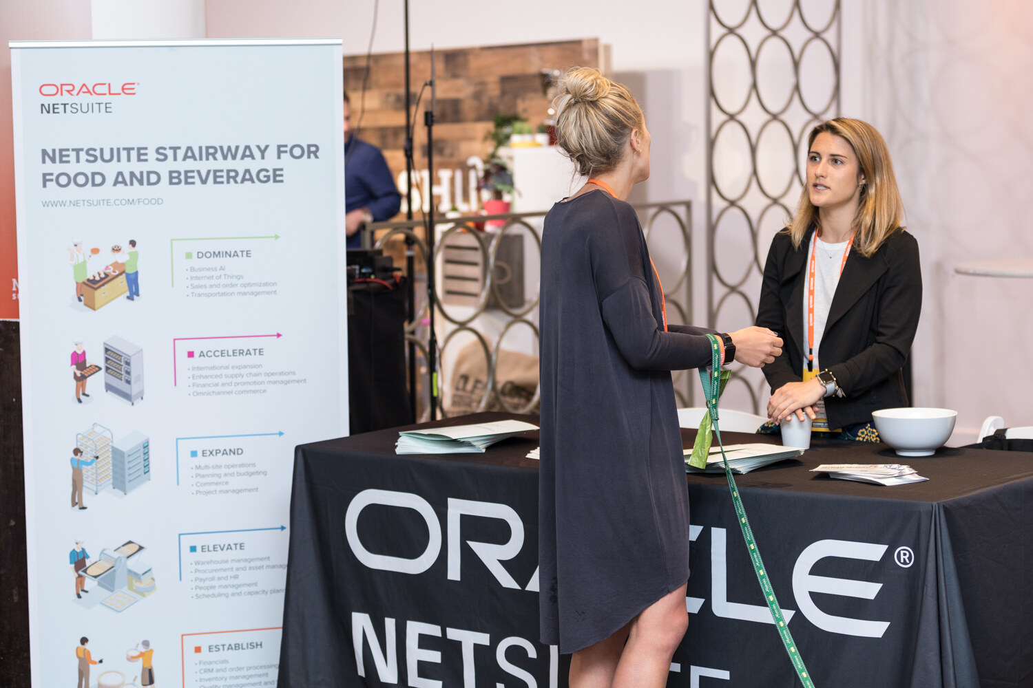 Oracle NetSuite stairway banner and booth with two women talking