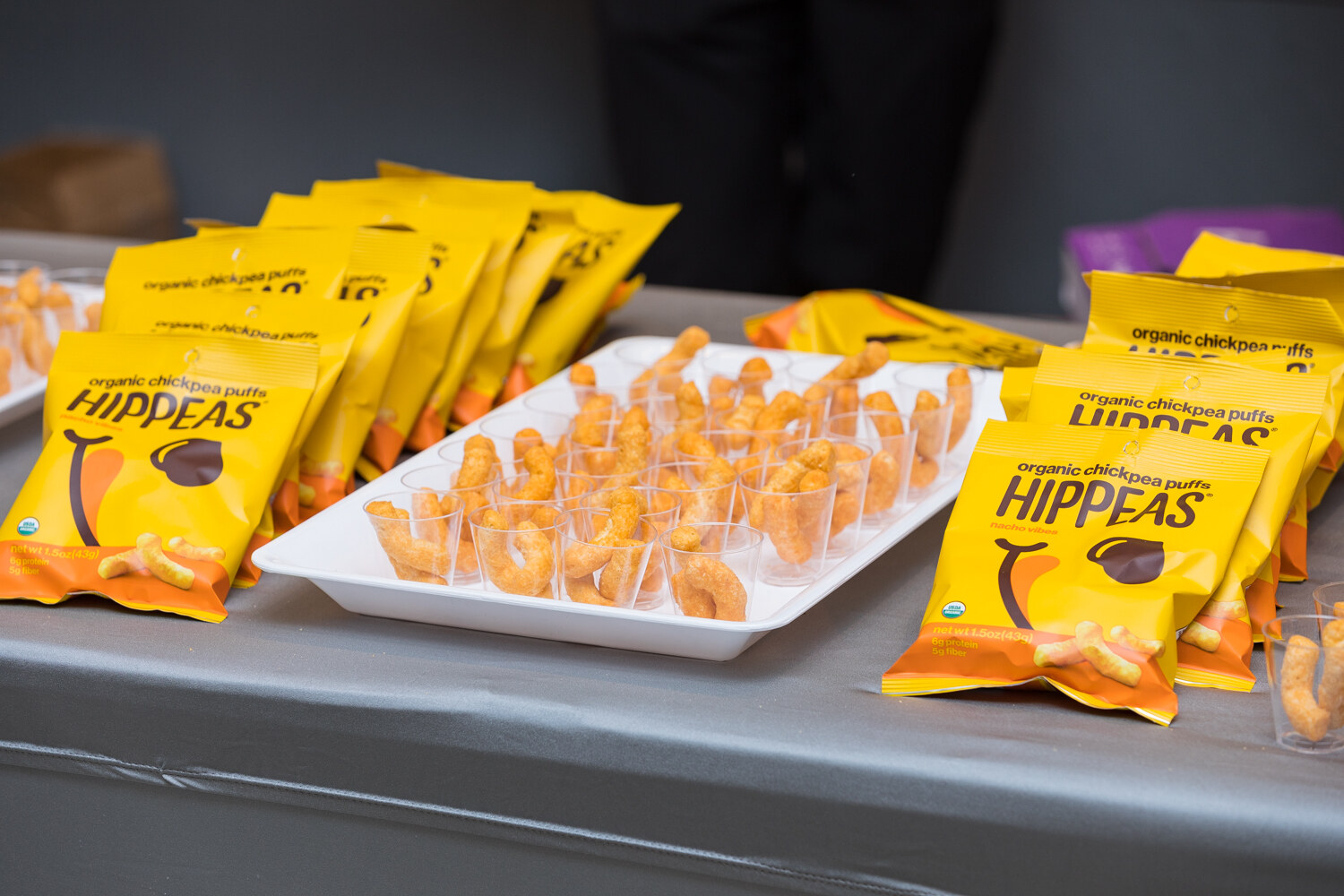 Hippeas organic chickpea puffs pouches with a tray of sample cups