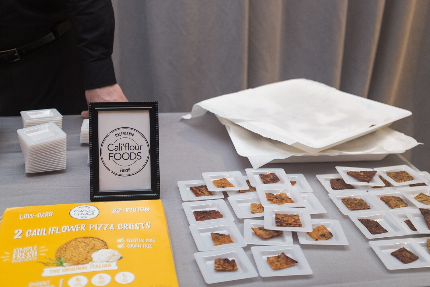 Cali'flour Foods sign beside small plates of pizza crust samples