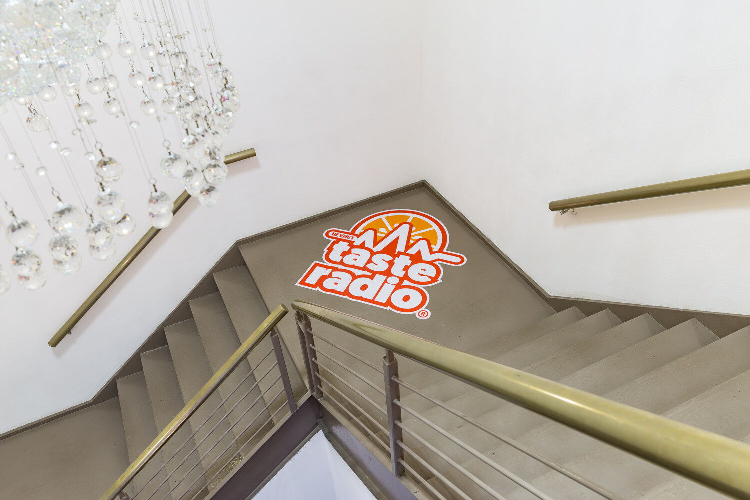 Taste Radio logo on a stair landing beneath a crystal chandelier