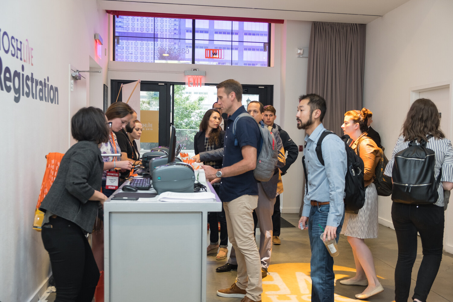 Attendees arriving in the foyer with a Registration sign on the wall