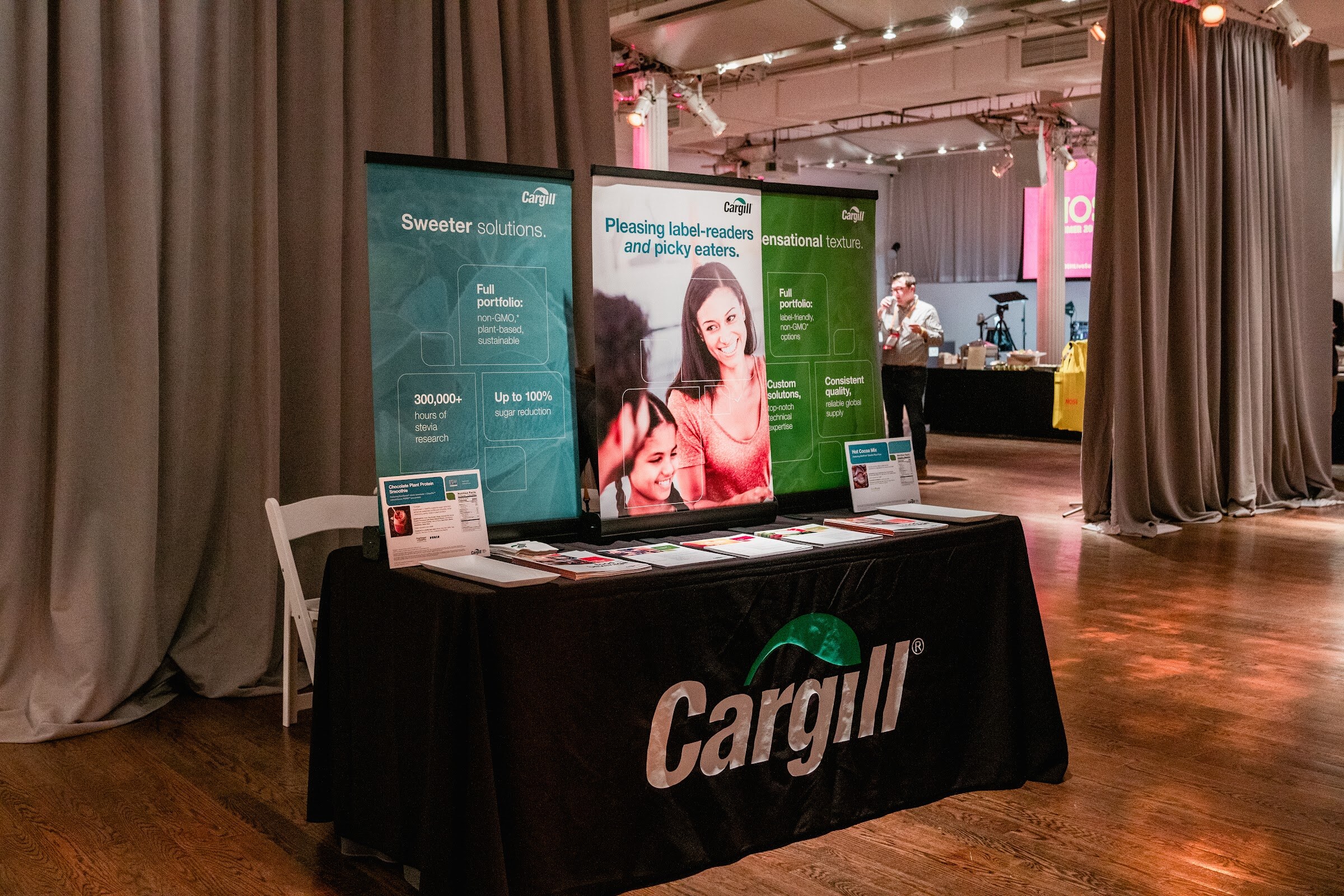 Black Cargill table with three banners reading Sweeter solutions and Pleasing label-readers and picky eaters against gray curtains.